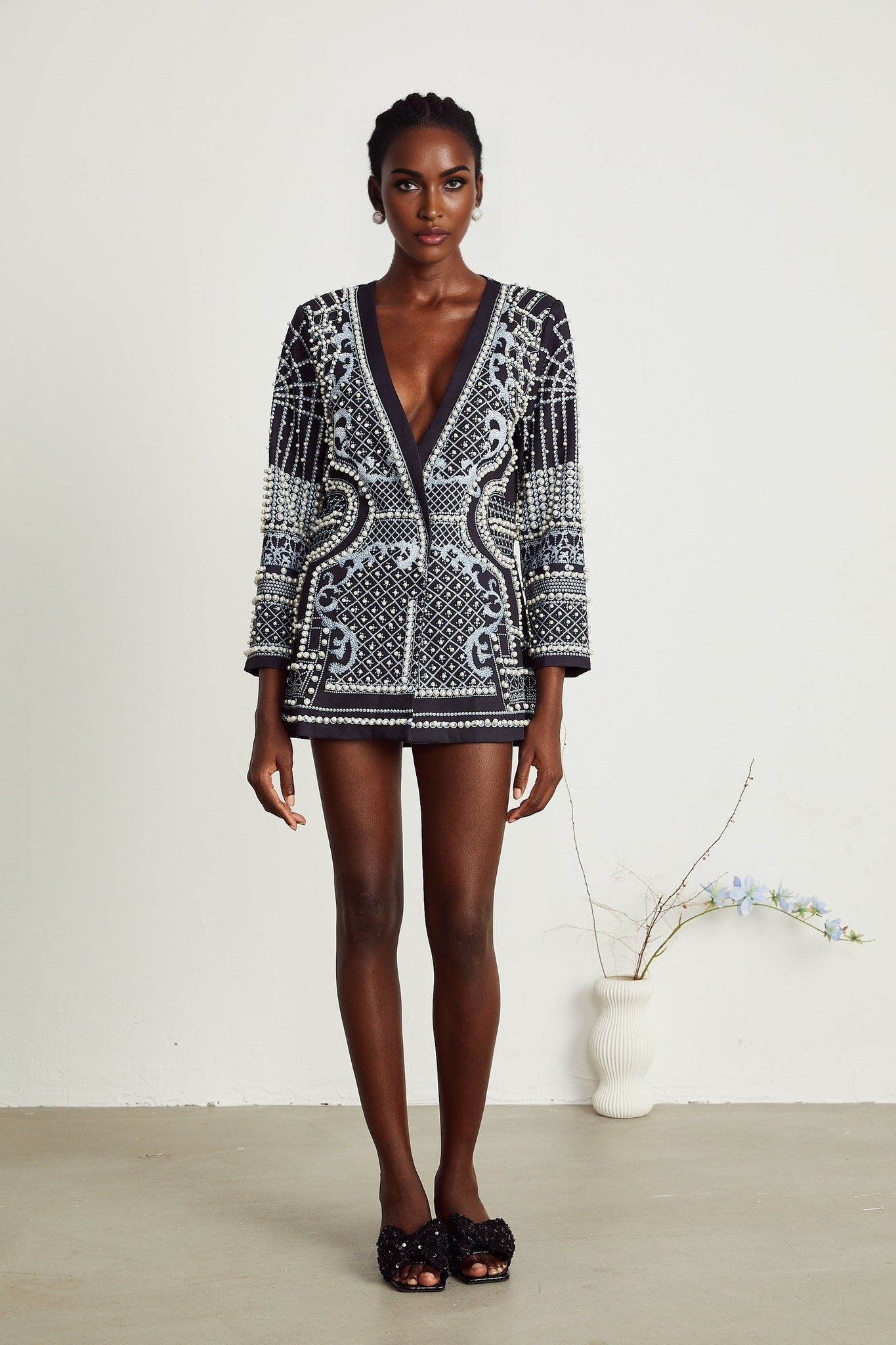 Woman wearing a blue and white patterned blazer dress with Vneck and short sleeves standing against plain background