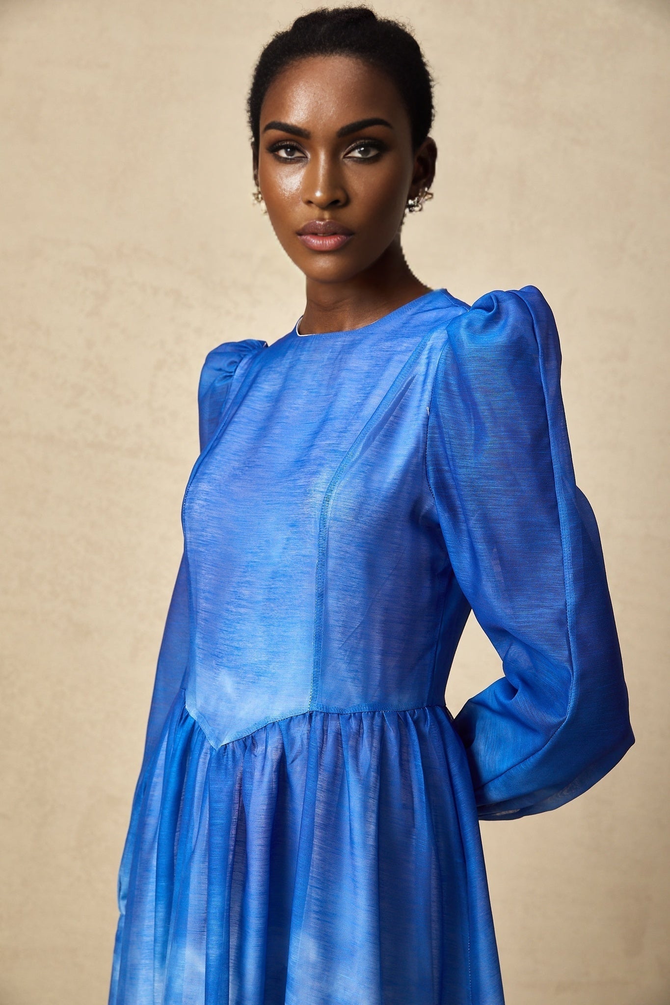 Woman wearing a blue gradient pleated midi dress with a flowing skirt and fitted bodice