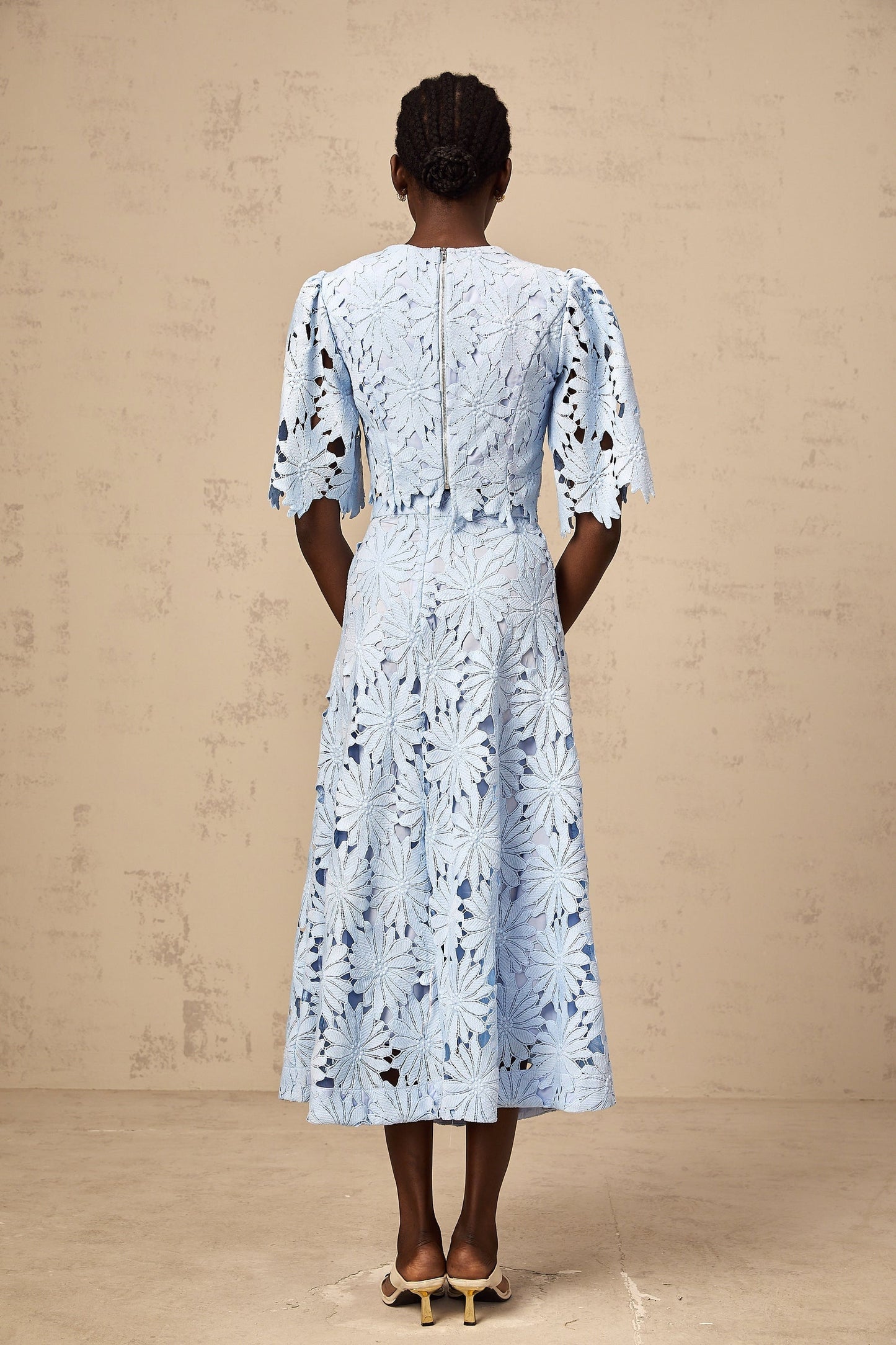 Woman wearing a blue lace top and matching skirt set in Audrey style with guipure lace detailing