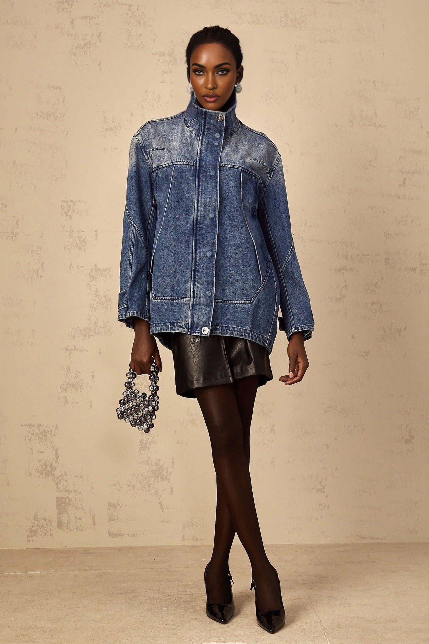 Woman wearing a blue patchwork denim jacket with loose fit and various shades of blue fabric panels