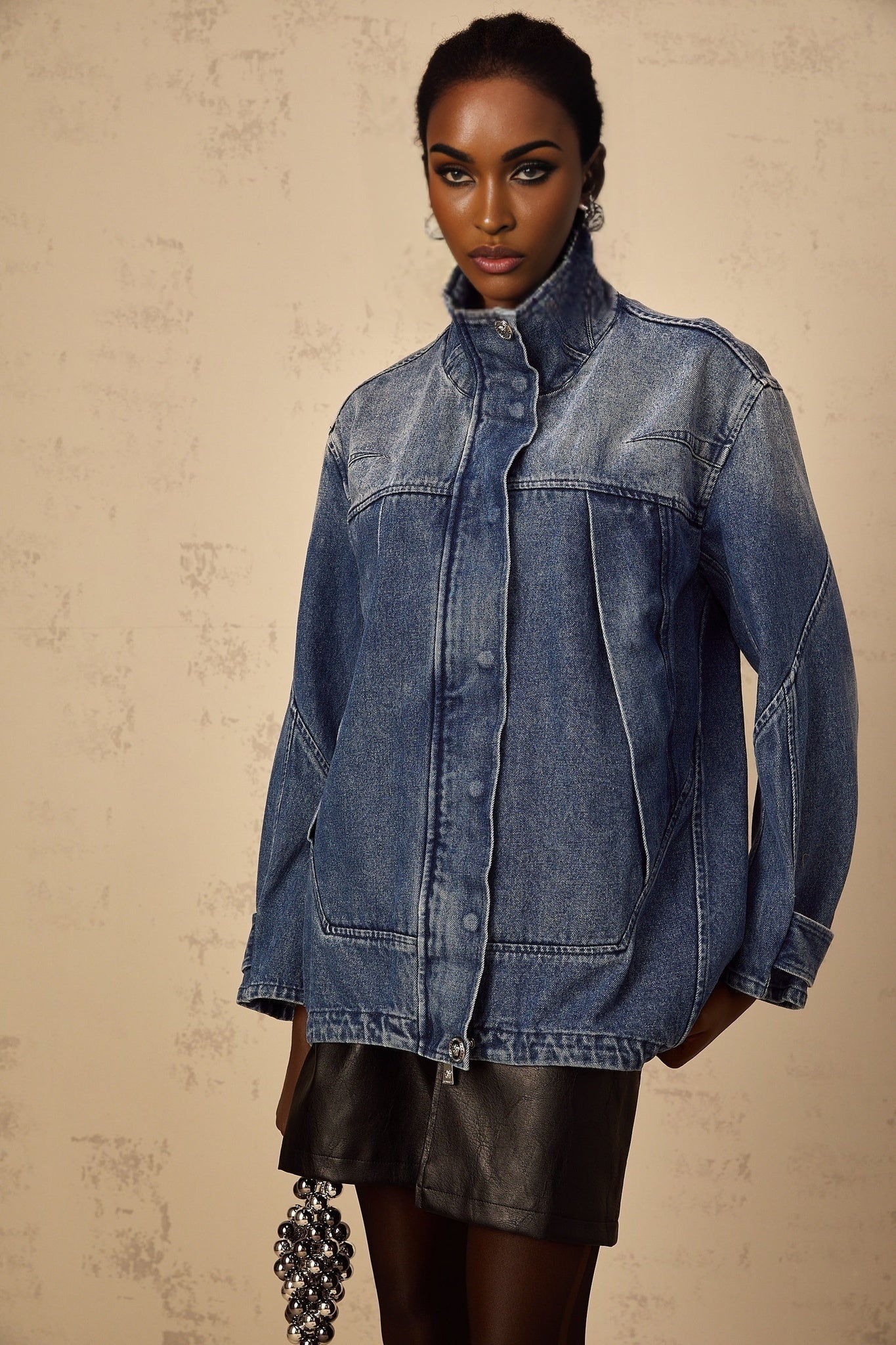 Woman wearing a blue patchwork denim jacket with loose fit design and various shades of blue fabric