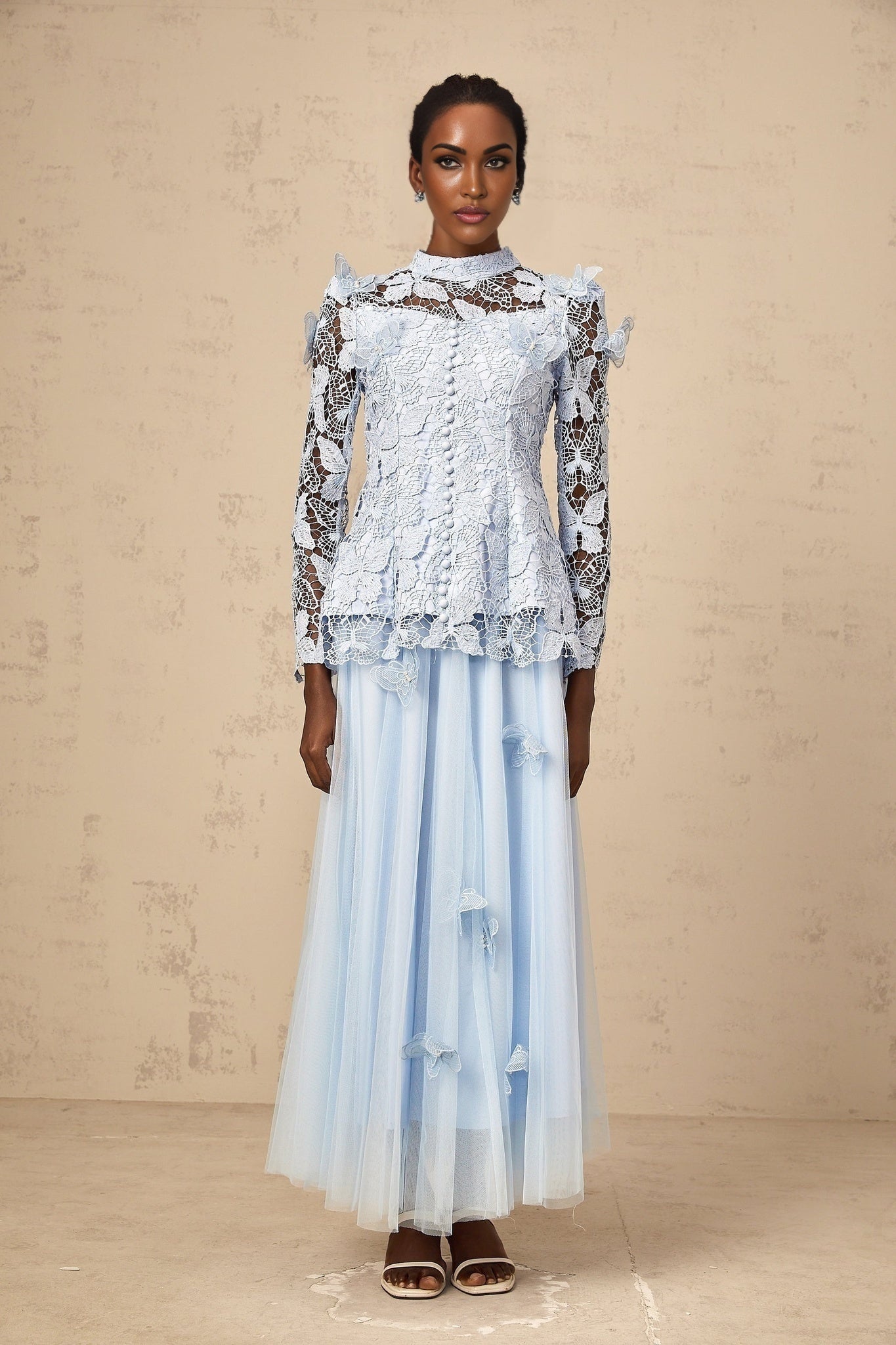 Woman wearing a blue sequined lace top and matching skirt set called Nicolette