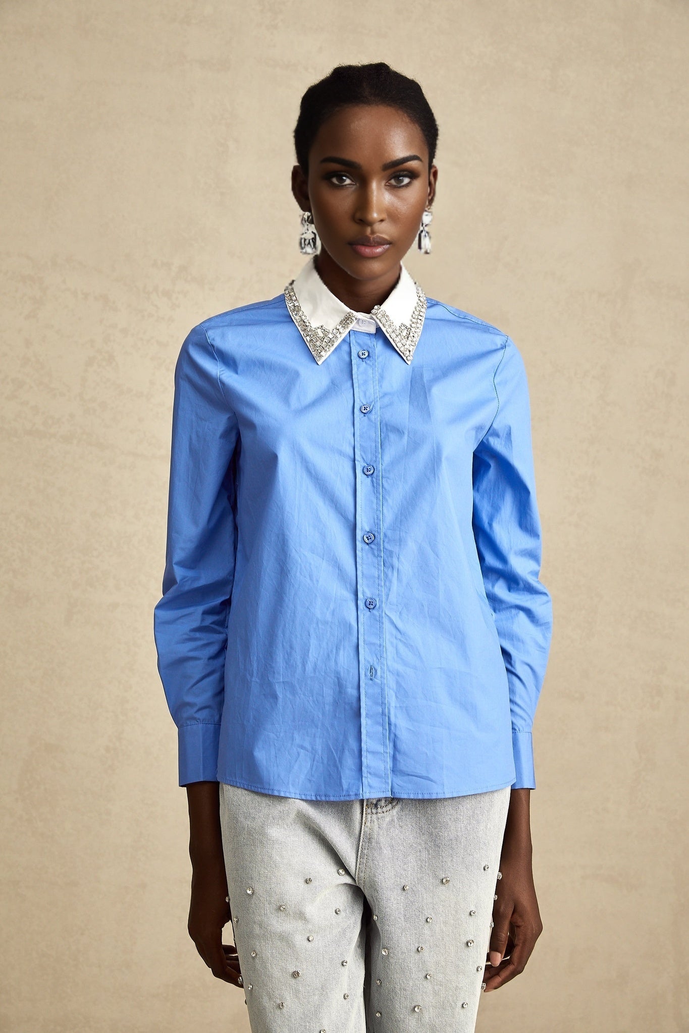 Woman wearing a blue shirt with rhinestone embellishments and color block design