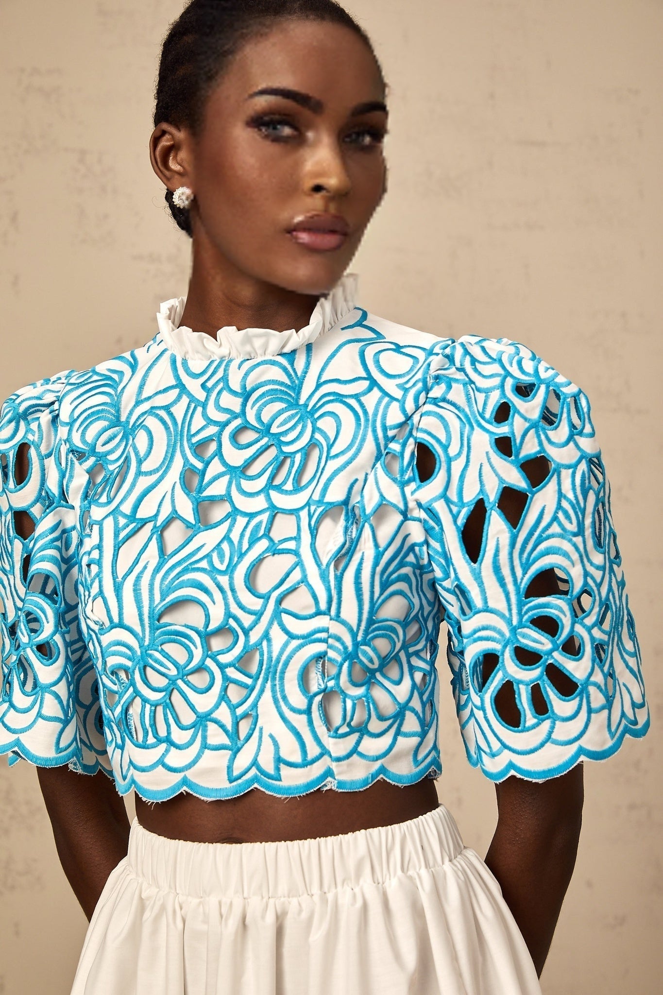 Woman wearing a blue two piece outfit consisting of a cut out top and skirt with embroidery details Aurore matching set