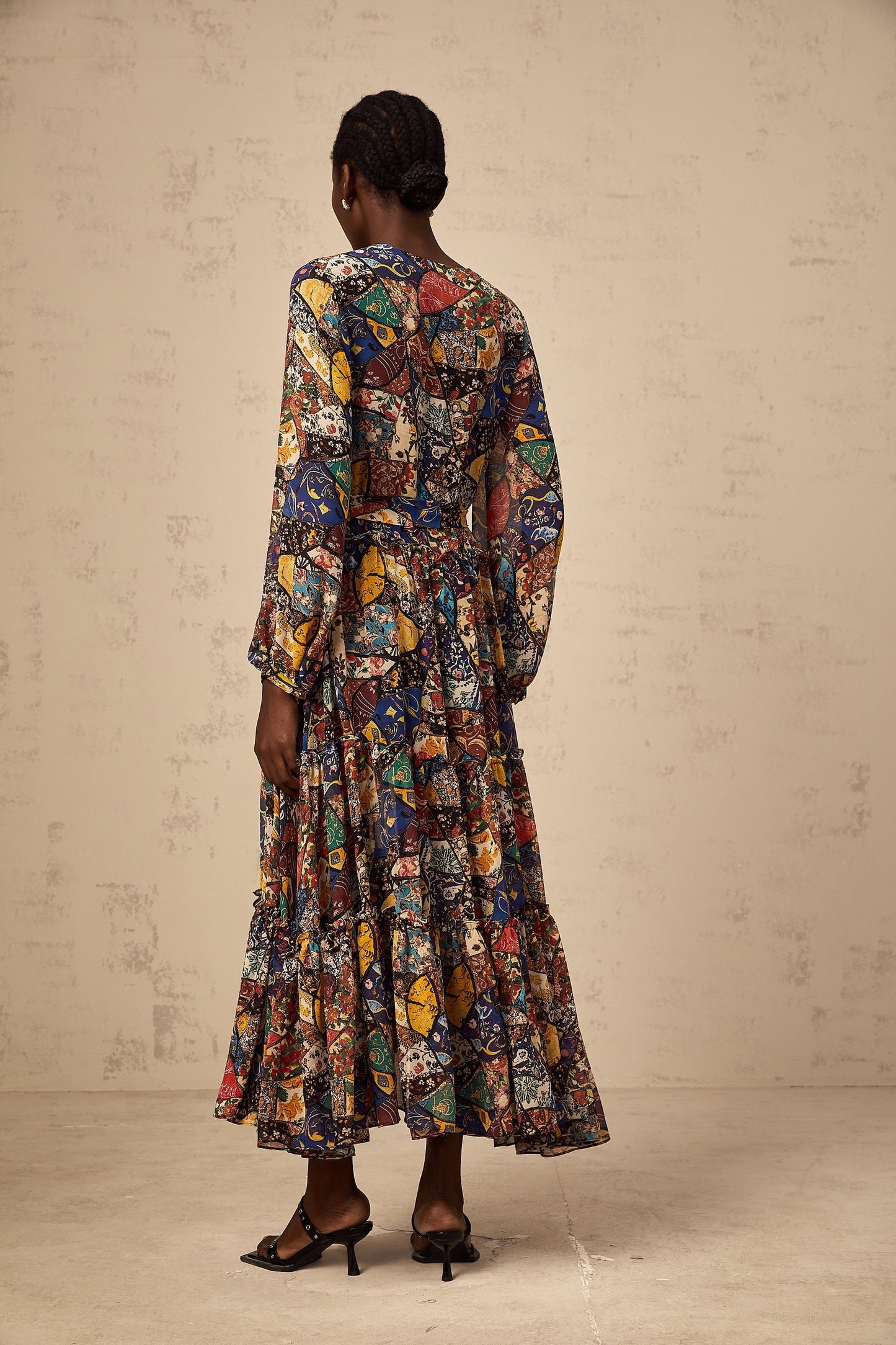 Woman wearing a brown bohemian style midi dress with shirring details and flowy sleeves in an outdoor setting