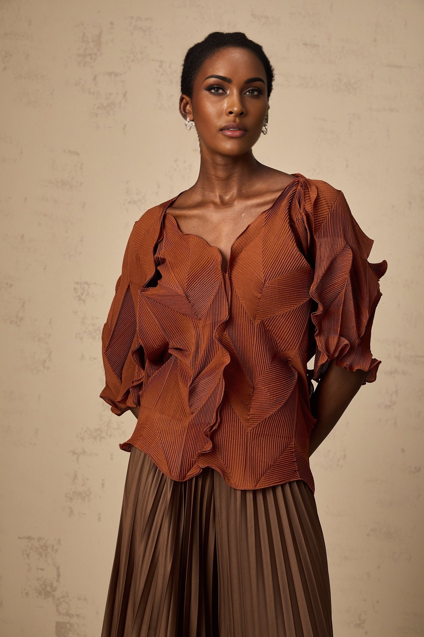 Woman wearing a brown matching set consisting of a creased top and skirt in demi shade