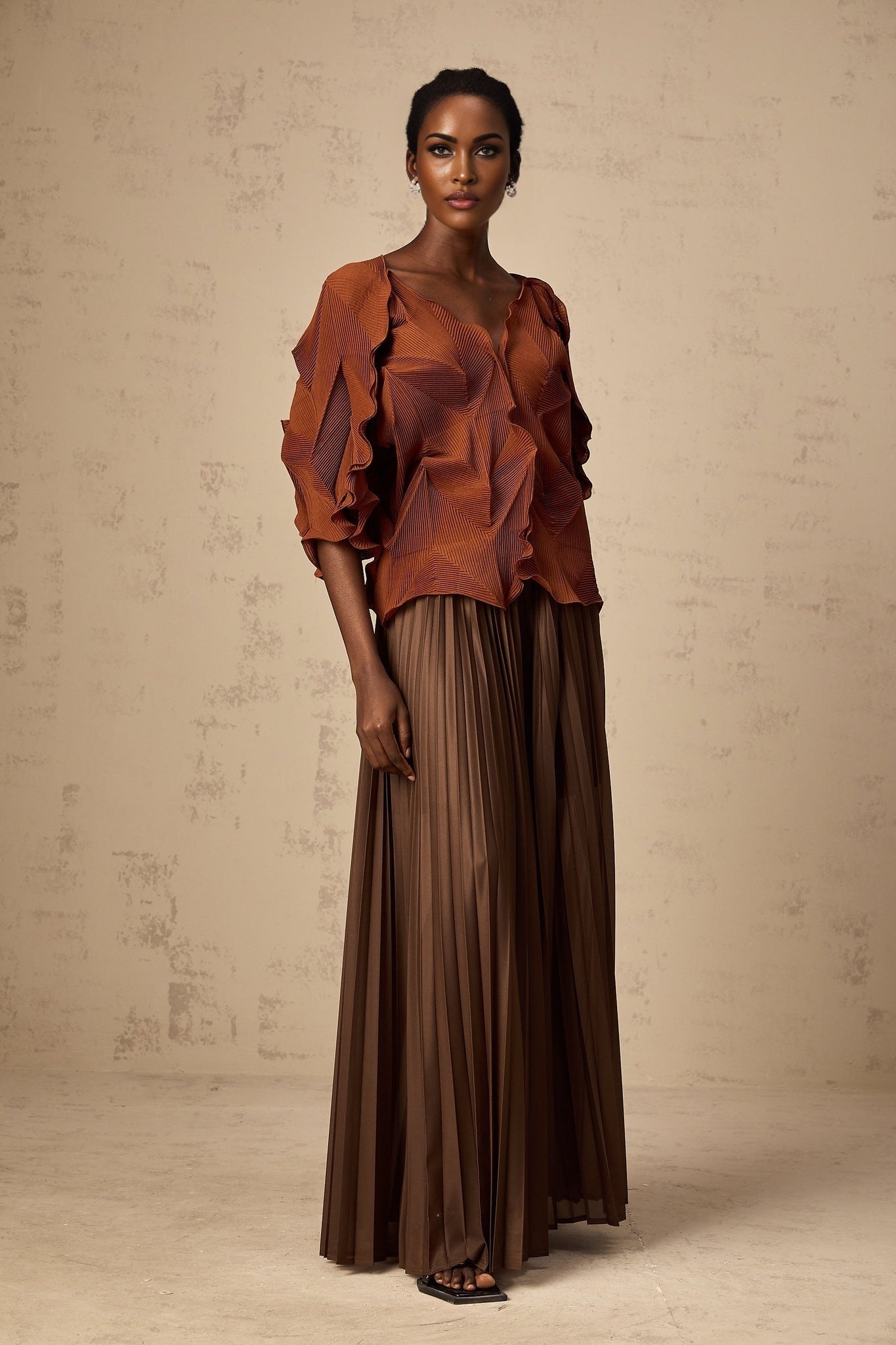 Woman wearing a brown matching set consisting of a creased top and skirt in demi style fabric