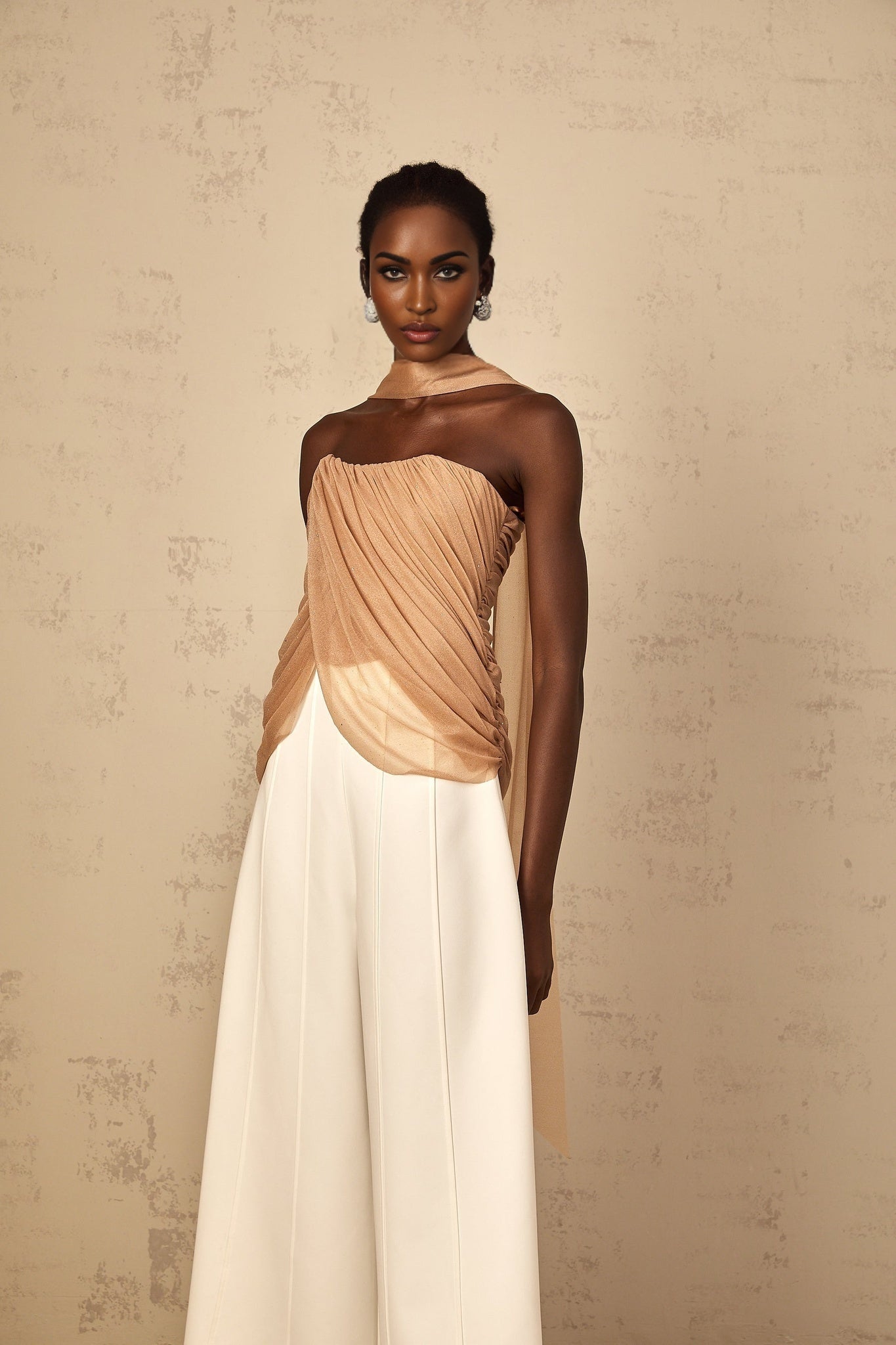 Woman wearing a brown sleeveless top with ruched tulle fabric and allover sequin embellishment