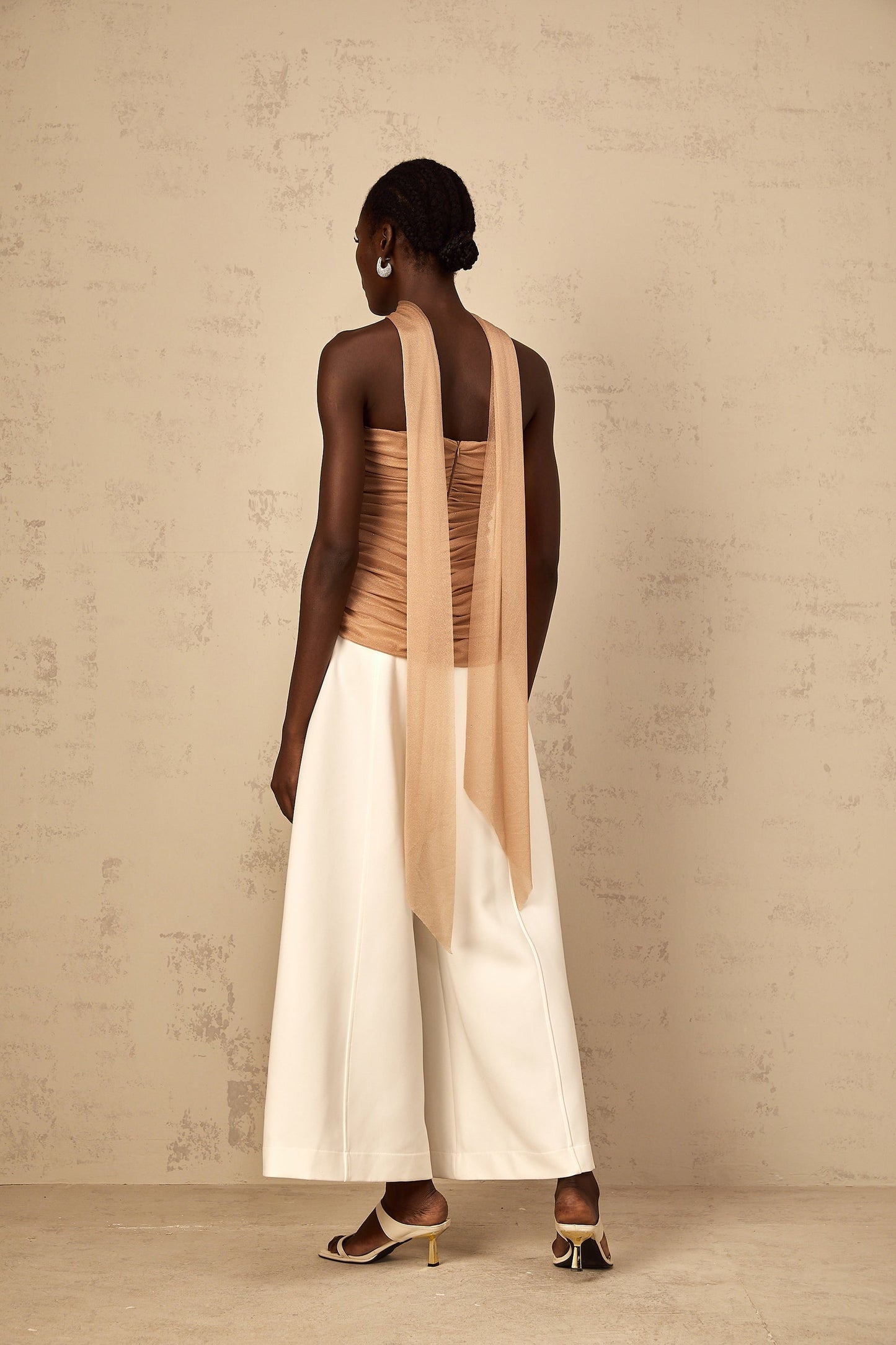 Woman wearing a brown sleeveless top with sequin embellishments and ruched tulle fabric