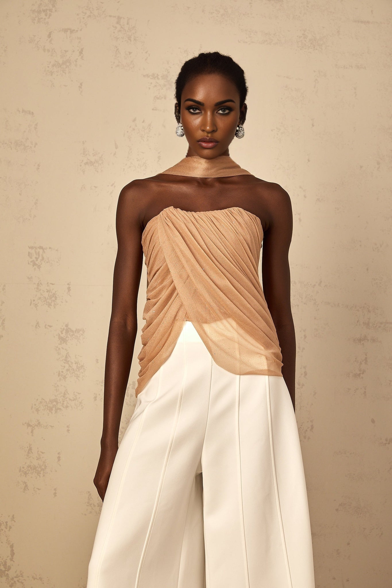 Woman wearing a brown sleeveless top with sequin embellishments and ruched tulle fabric