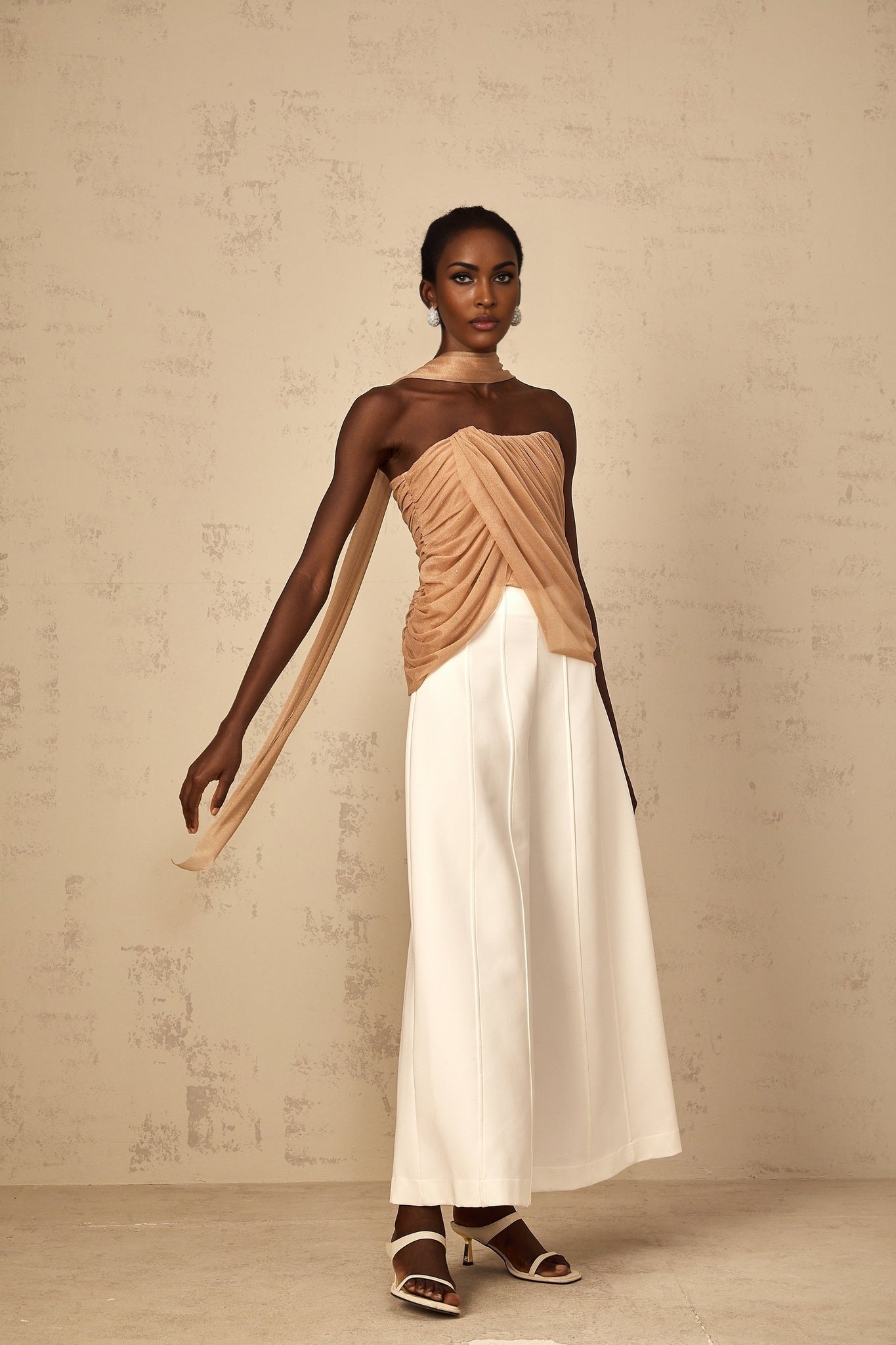 Woman wearing a brown sleeveless top with sequin embellishments and ruched tulle fabric