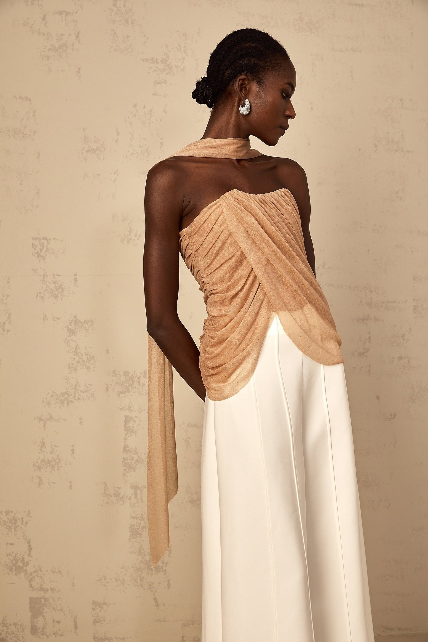 Woman wearing a brown sleeveless top with sequin embellishments and ruched tulle fabric