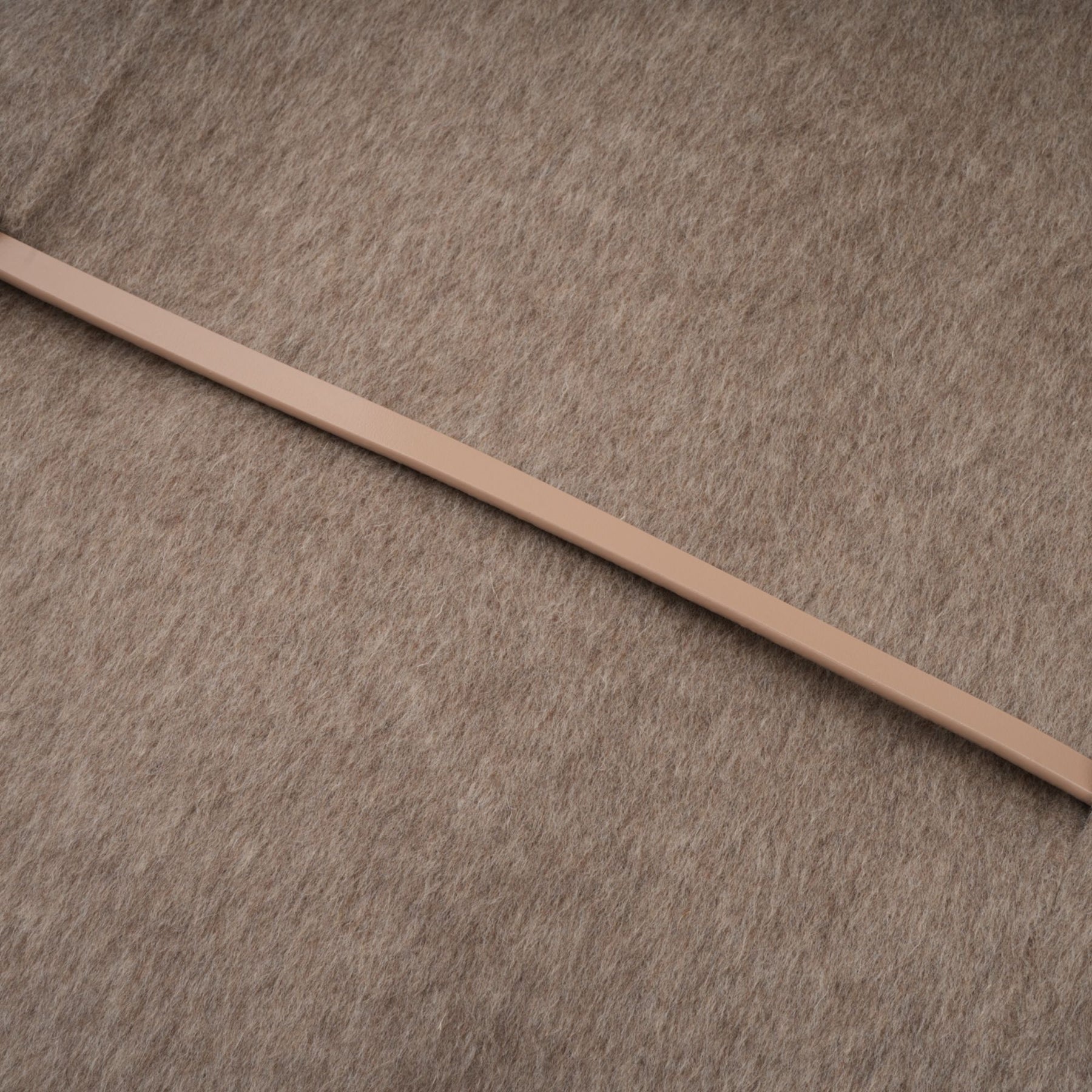 Woman wearing a brown wool cape coat with fur trim and belt cinched at the waist standing against neutral background