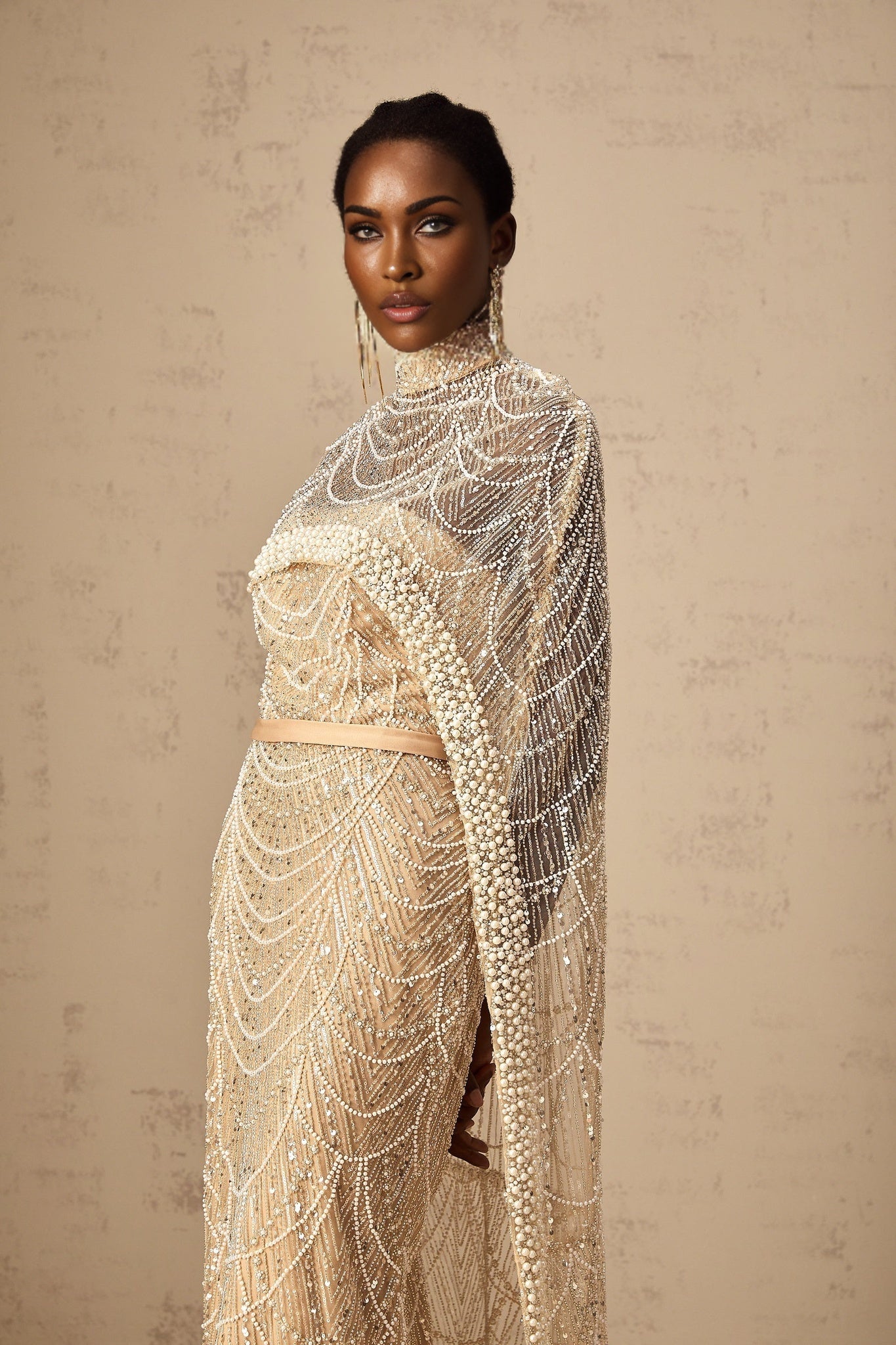 Woman wearing a champagne colored beaded gown with matching cape elegant formal attire for special occasions