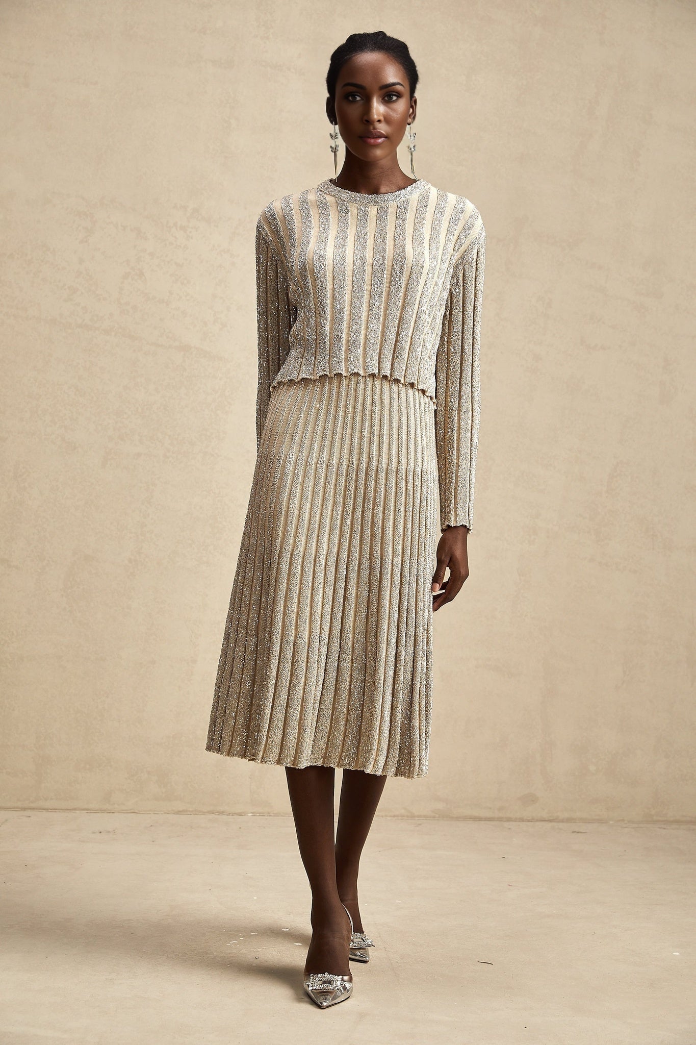 Woman wearing a champagne colored knit top and matching skirt with subtle vertical stripes in a coordinated set