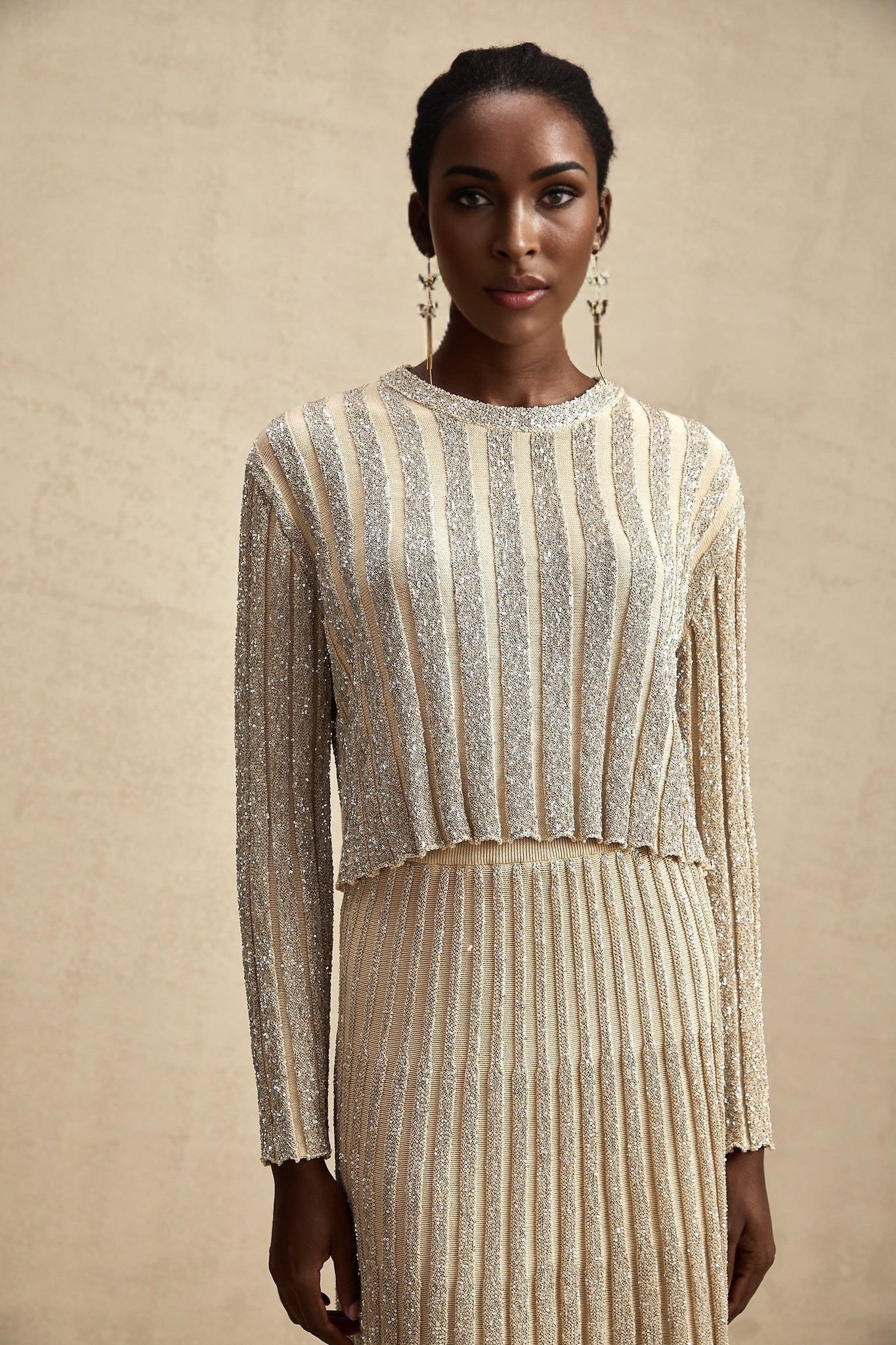 Woman wearing a champagne colored striped knit top and matching skirt set