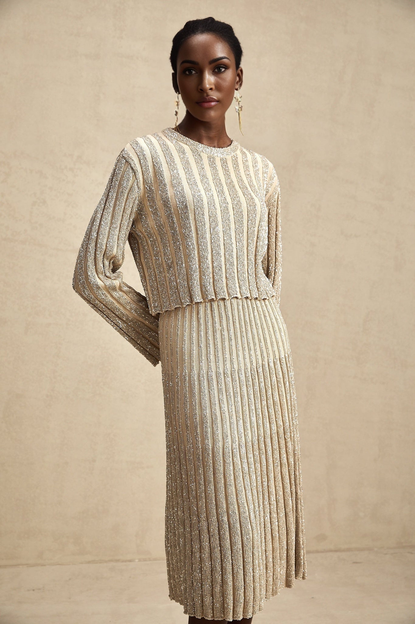 Woman wearing a champagne colored striped knit top and matching skirt set