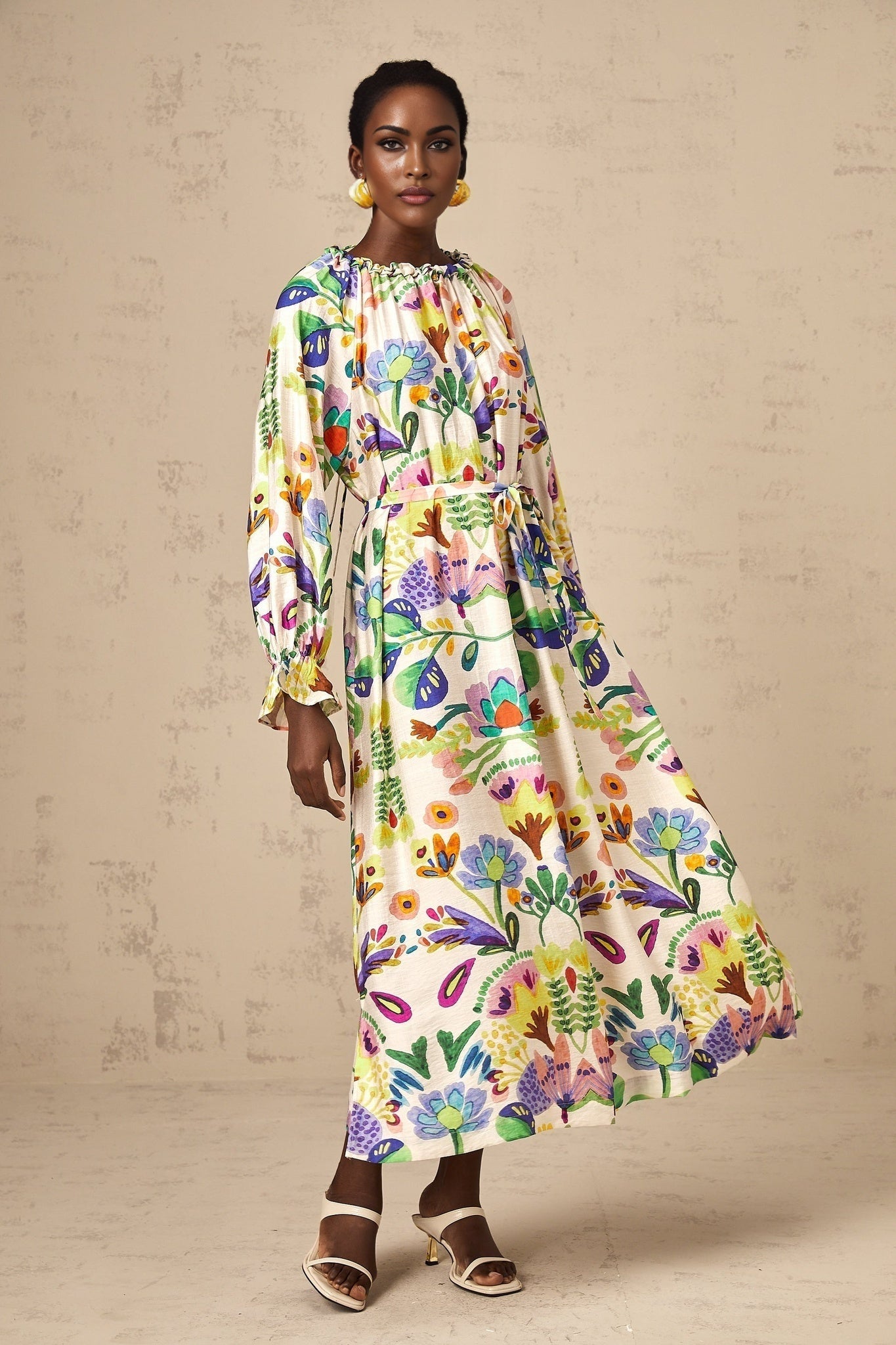 Woman wearing a colorful paisley print midi dress with short sleeves and a flowing skirt standing in a relaxed pose
