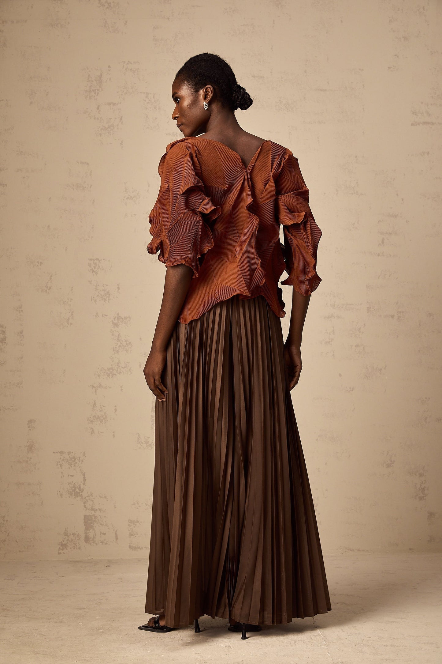 Woman wearing a demi brown matching set with creased top and skirt