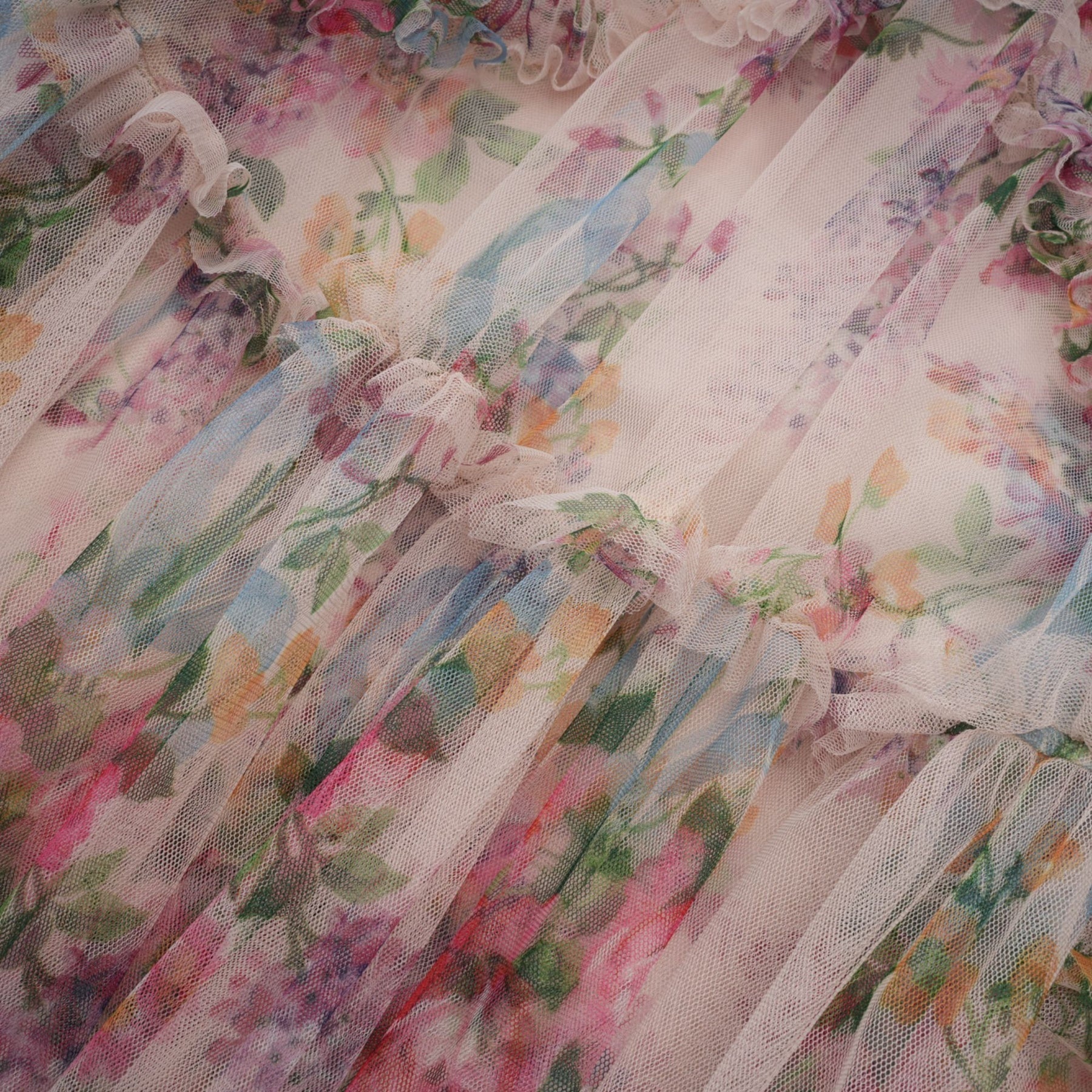 Woman wearing a floral midi dress with ruffled tulle details and a delicate floral pattern