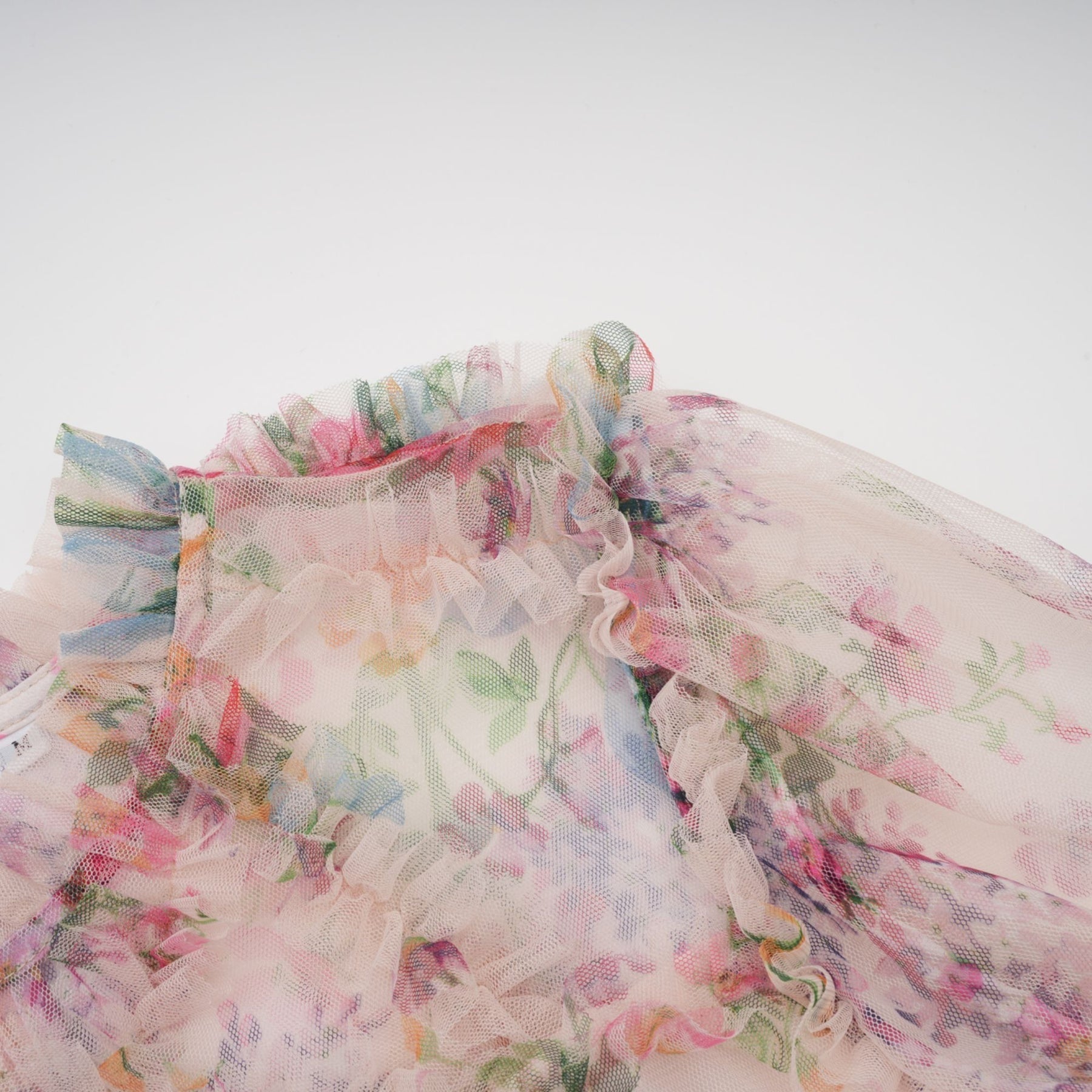 Woman wearing a floral patterned midi dress with ruffled tulle details and a flowing silhouette