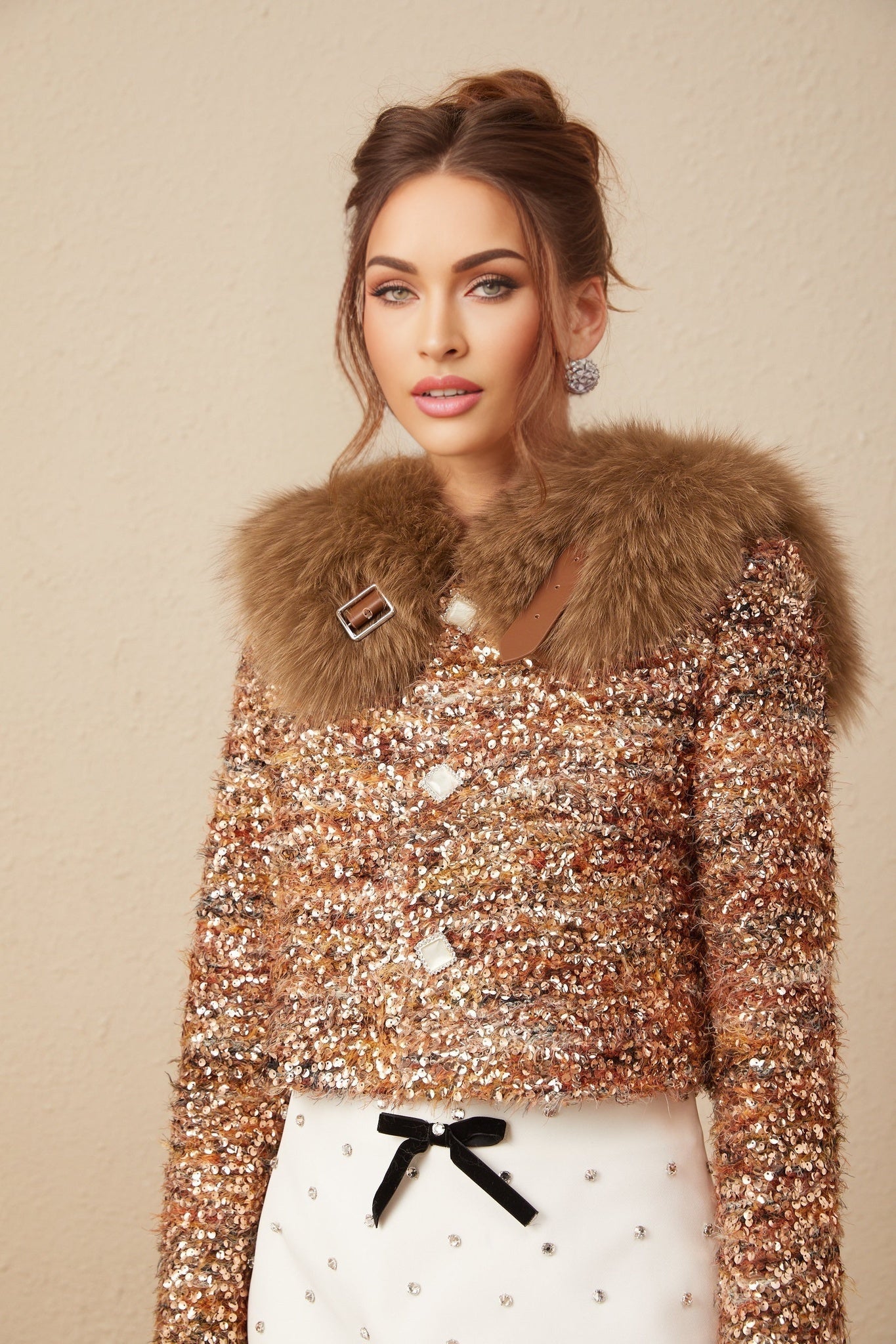 Woman wearing a gold sequined jacket with fur trim and long sleeves