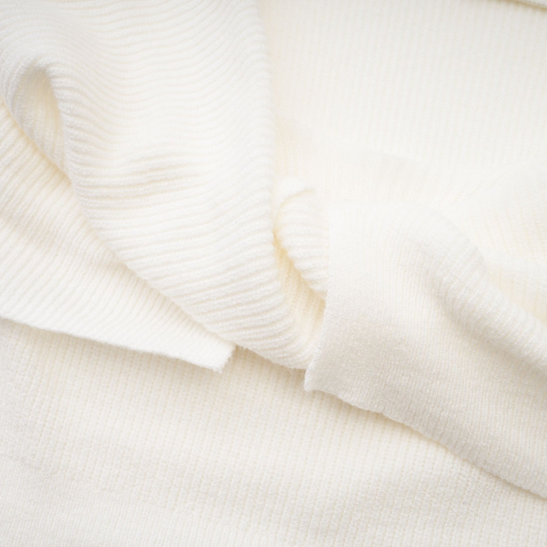 Woman wearing a knitted strapless long sleeve top in beige color standing against a plain background