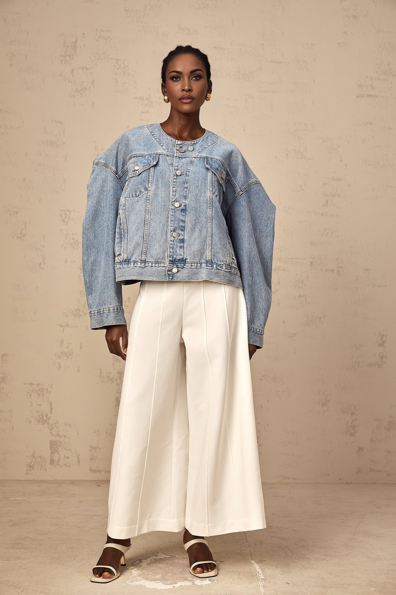 Woman wearing a light blue collarless denim jacket with front pockets and button closure