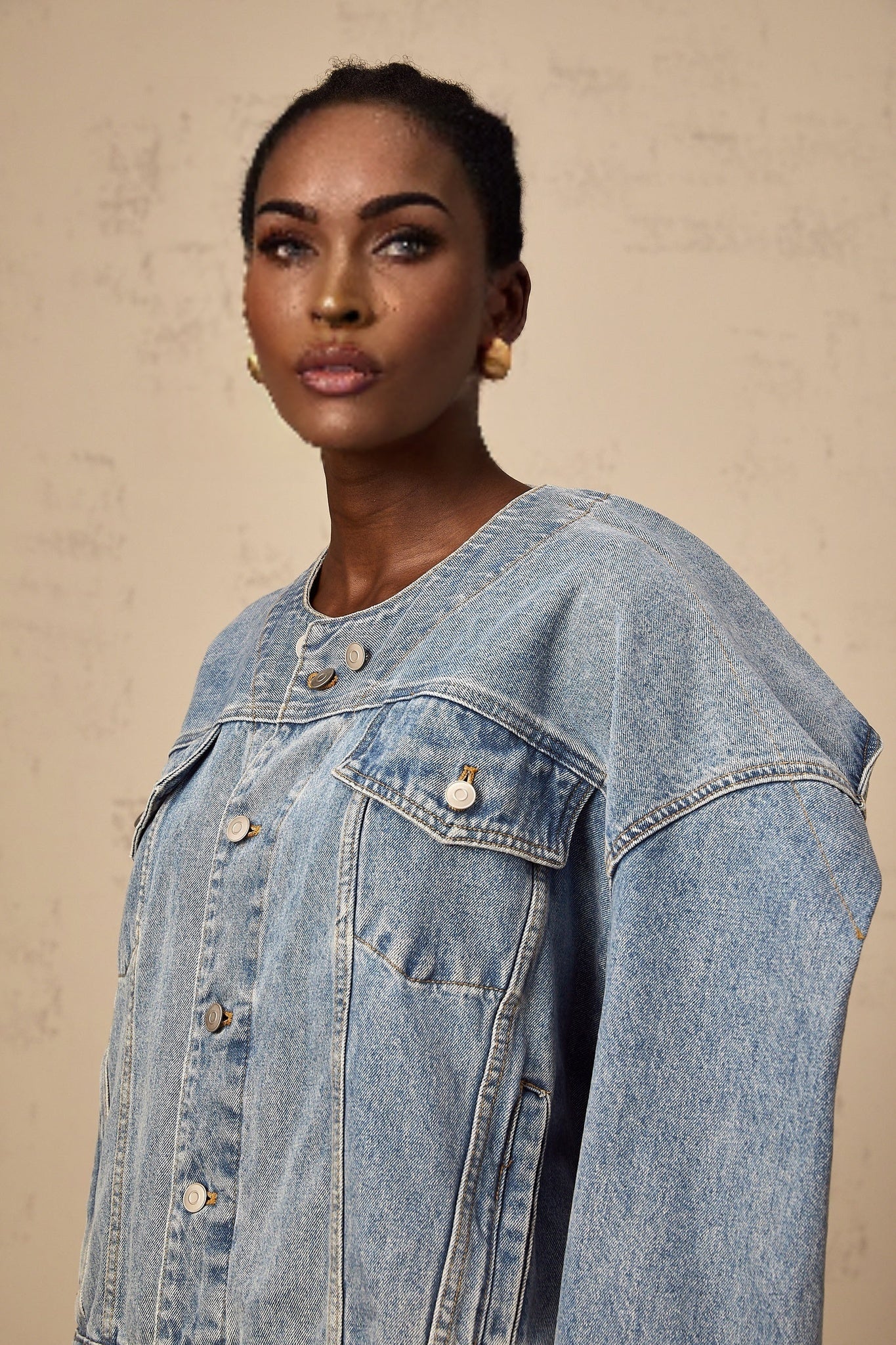 Woman wearing a light blue collarless denim jacket with long sleeves and button front closure