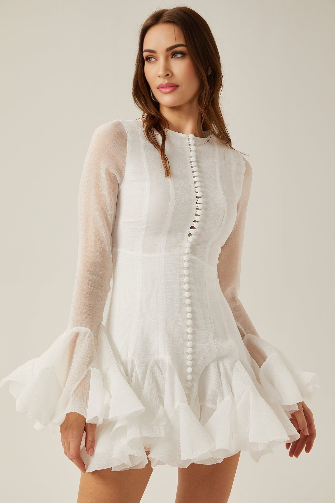 Woman wearing a light flowy semi sheer mini dress with flared skirt and short sleeves standing in relaxed pose