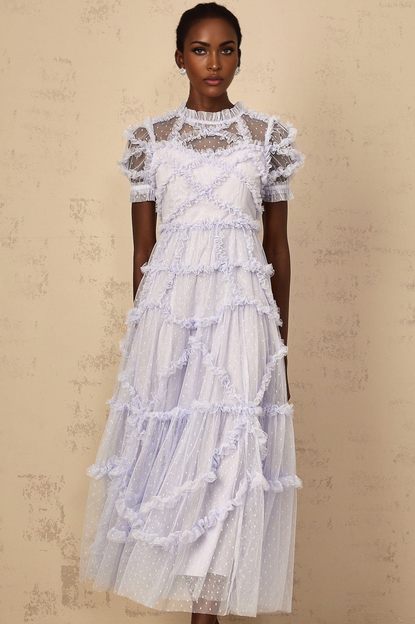 Woman wearing a long blue maxi dress with white polka dots and ruffled tulle details