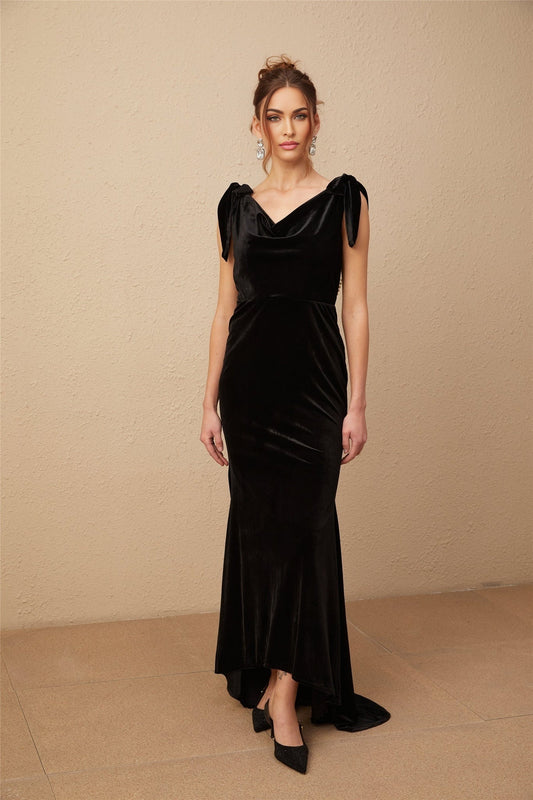 Woman wearing a long dark velvet dress with embellishments and an open back design