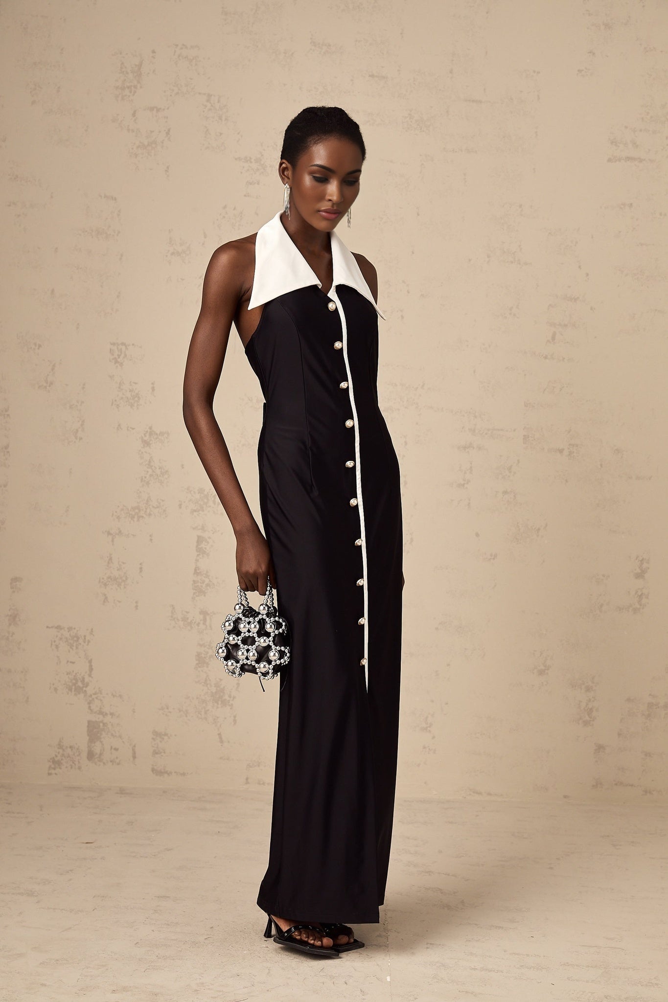 Woman wearing a long fitted maxi dress with colorblocked design in contrasting shades standing against a plain background