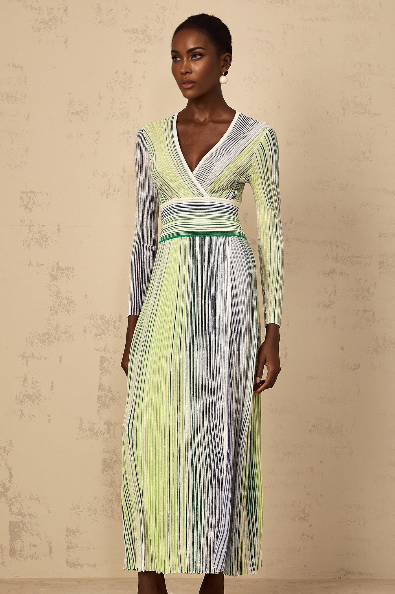 Woman wearing a long green knit maxi dress with long sleeves and sequin striped pattern