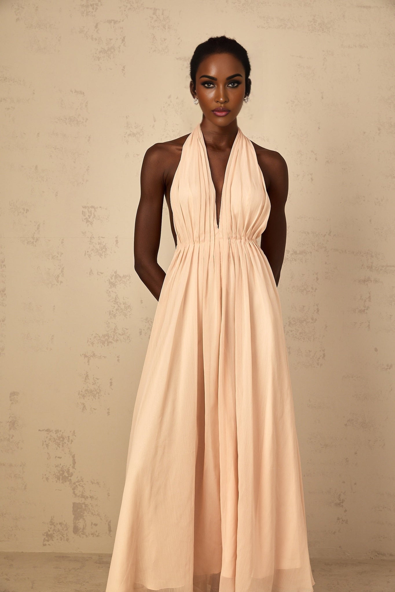 Woman wearing a long halterneck maxi dress with shirred bodice and flowing tulle skirt