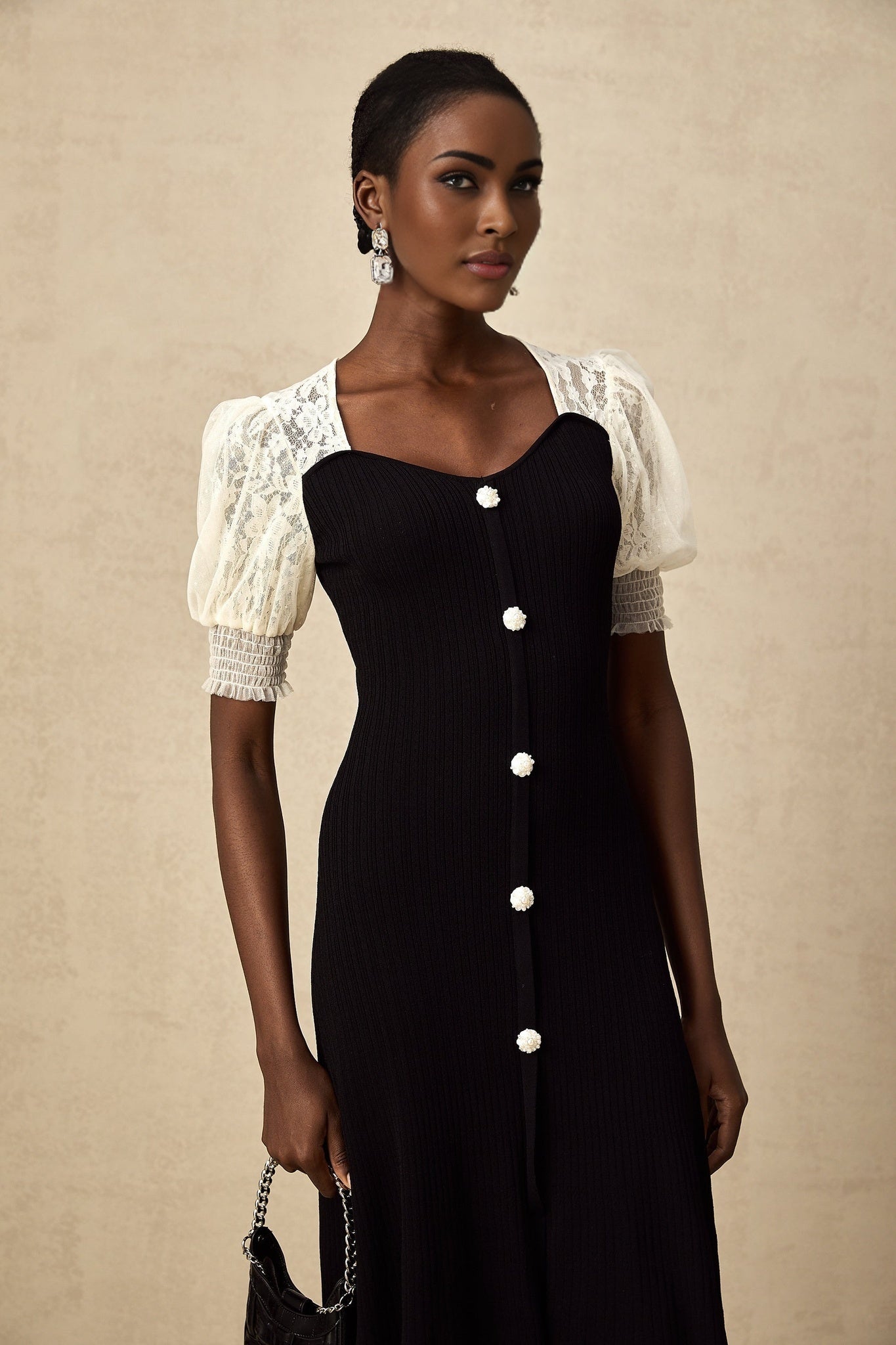 Woman wearing a long knit midi dress with lace trim details and a fitted silhouette in a neutral color