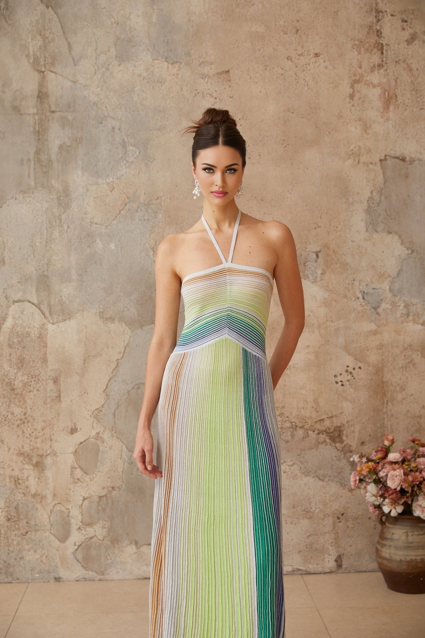 Woman wearing a long metallic knit maxi dress with backless design standing in elegant pose