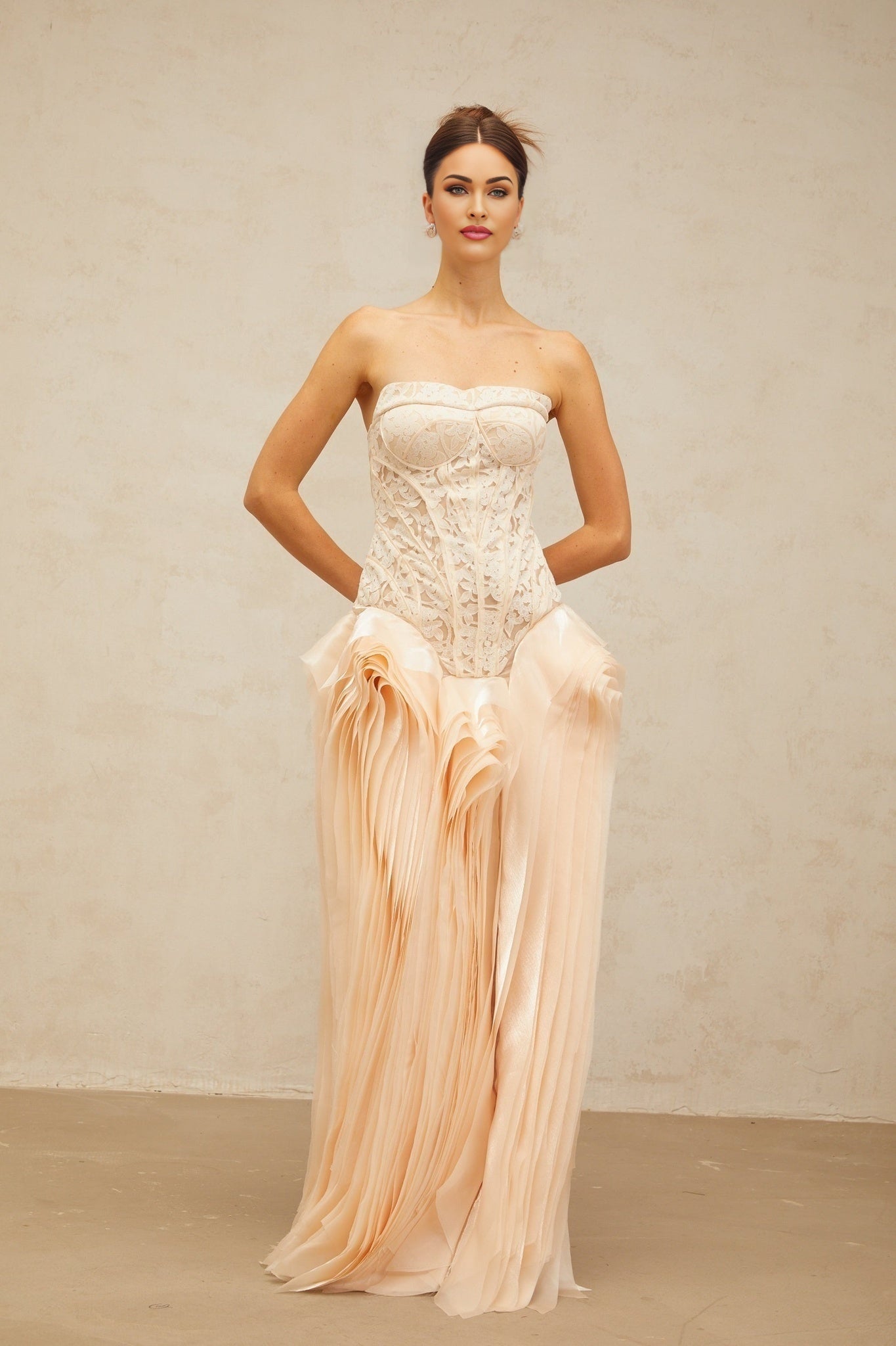 Woman wearing a long neutral colored lace corset maxi dress with layered details and delicate straps