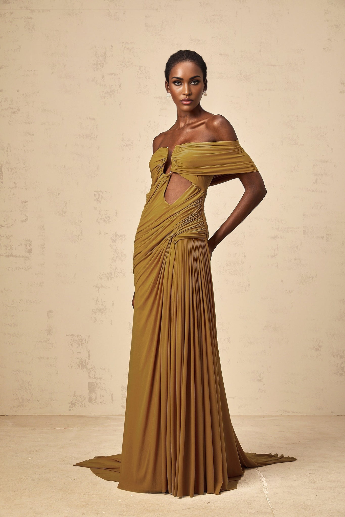 Woman wearing a long ocher maxi dress with offshoulder design ruched details and cut out sections