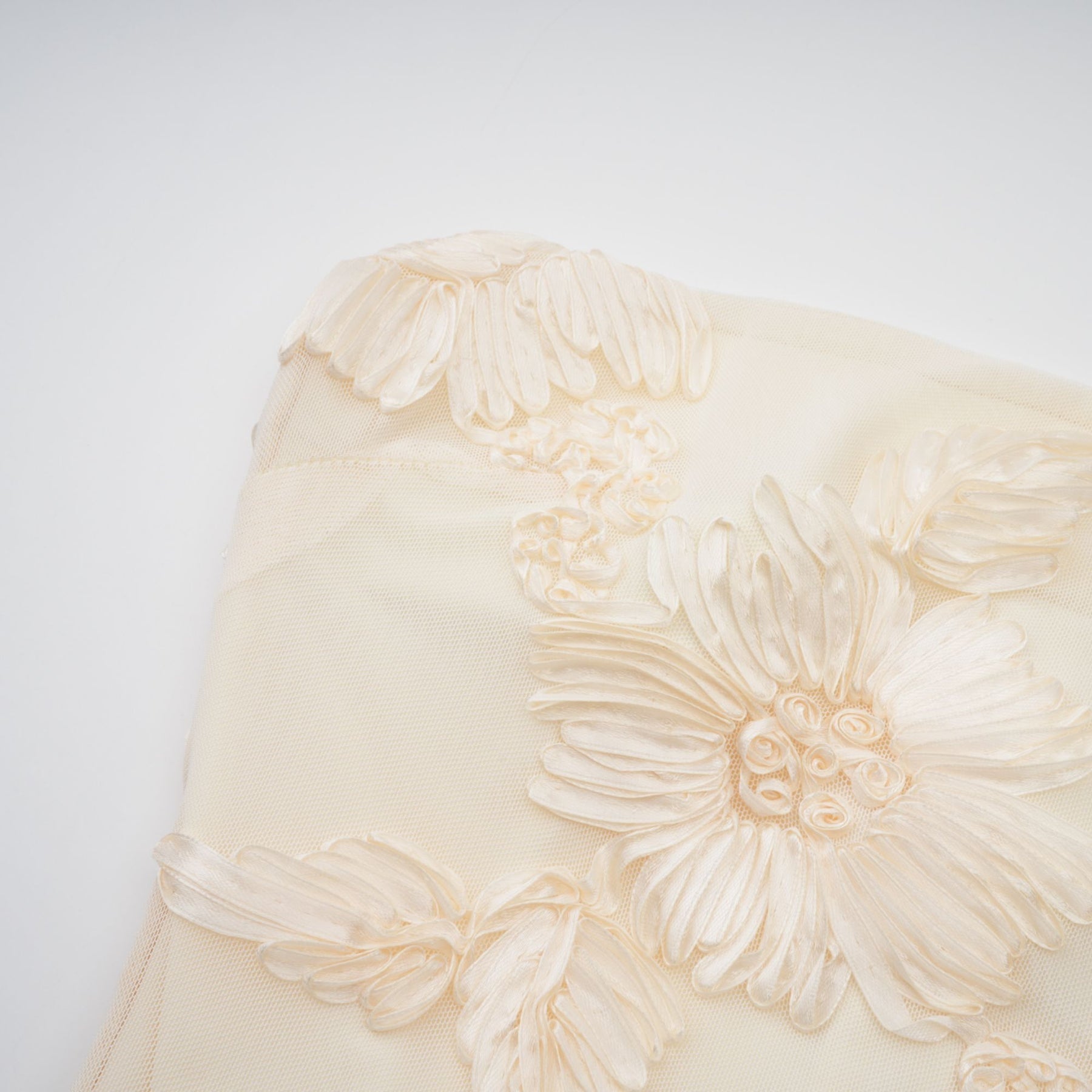 Woman wearing a long offshoulder maxi dress in neutral tones with embroidered details