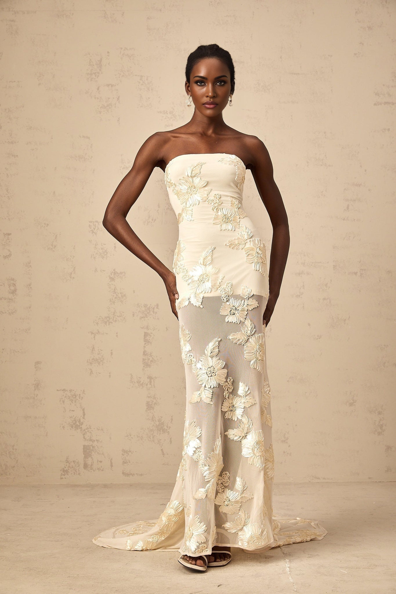 Woman wearing a long offshoulder maxi dress in neutral tones with embroidered details