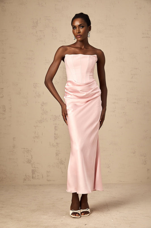 Woman wearing a long pink offshoulder maxi dress with flowy fabric standing in a relaxed pose