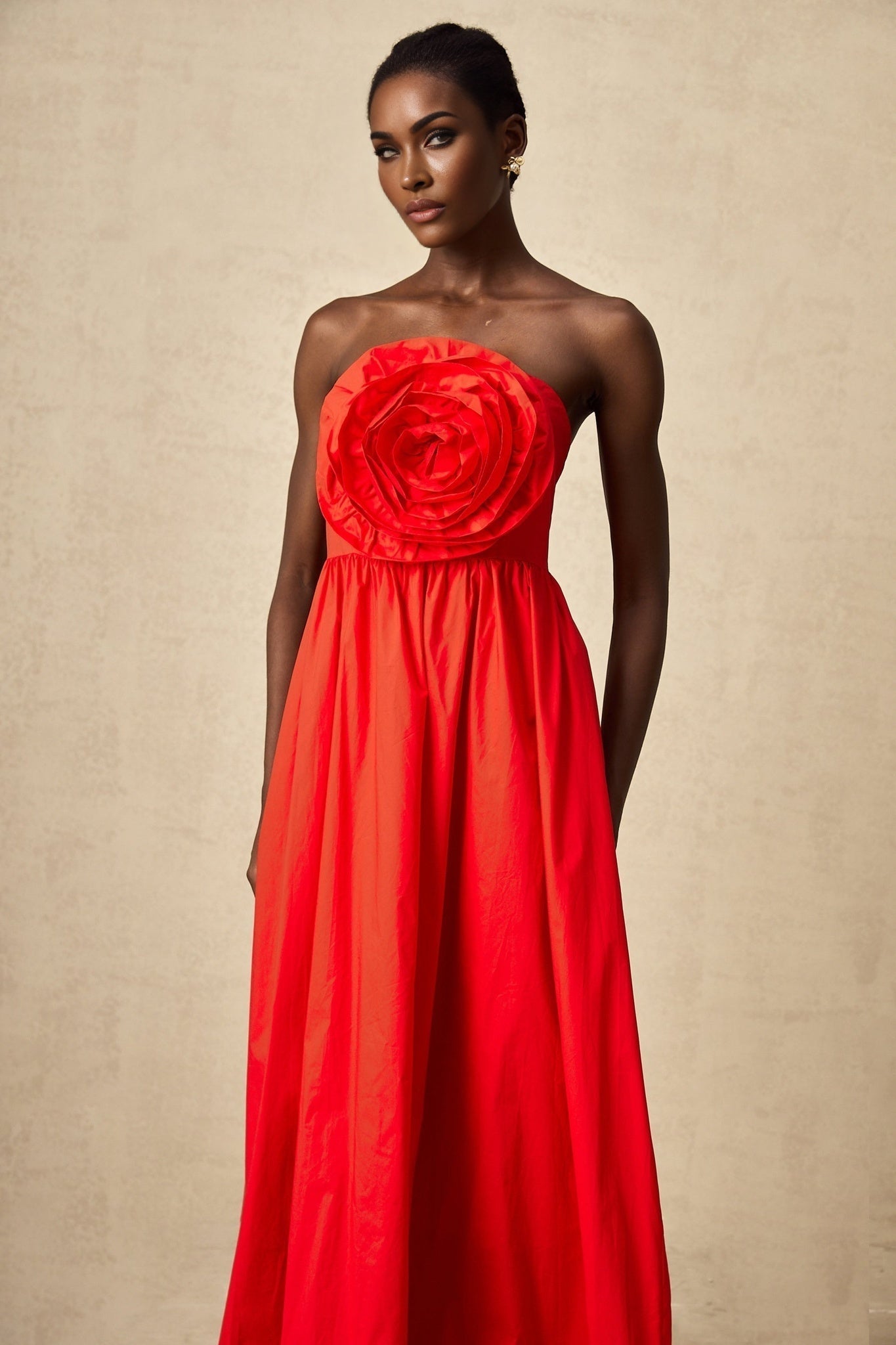 Woman wearing a long red maxi dress with layered 3d petal ruffles cascading down the skirt