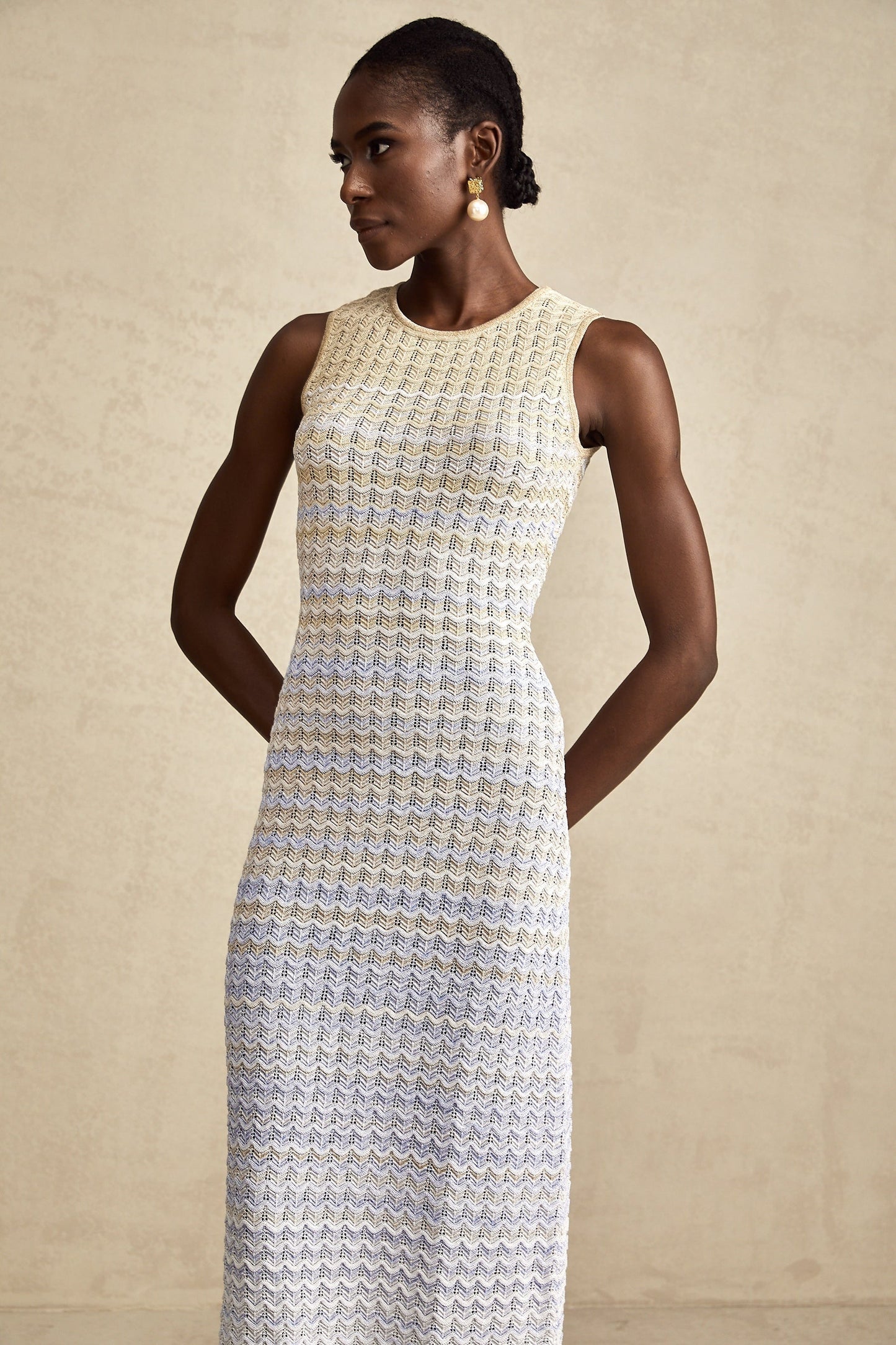Woman wearing a long ribbed knit dress with contrasting color details and midi length