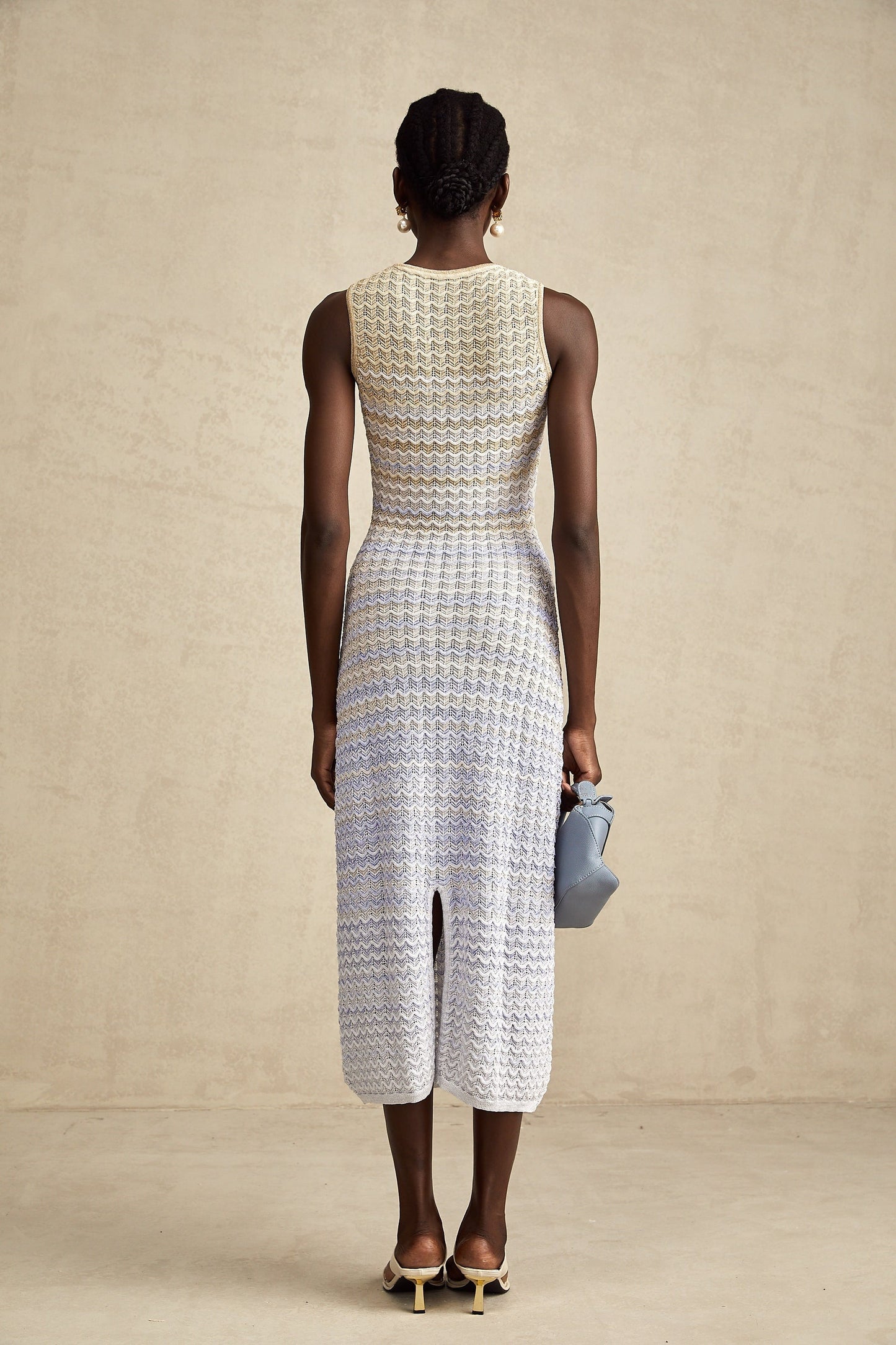 Woman wearing a long ribbed knit dress with contrasting color details and midi length