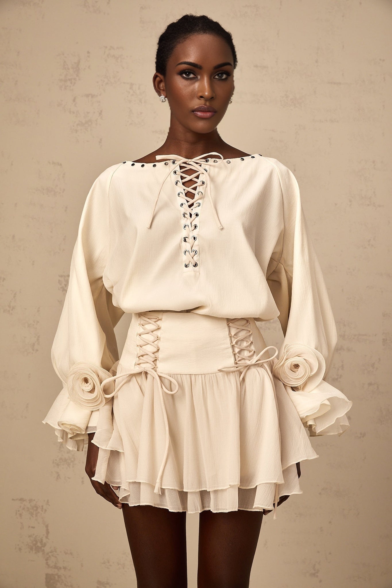 Woman wearing a matching blouse and skirt set in light fabric The blouse has ruffles and a self tie detail The skirt is flowy and coordinated with the top
