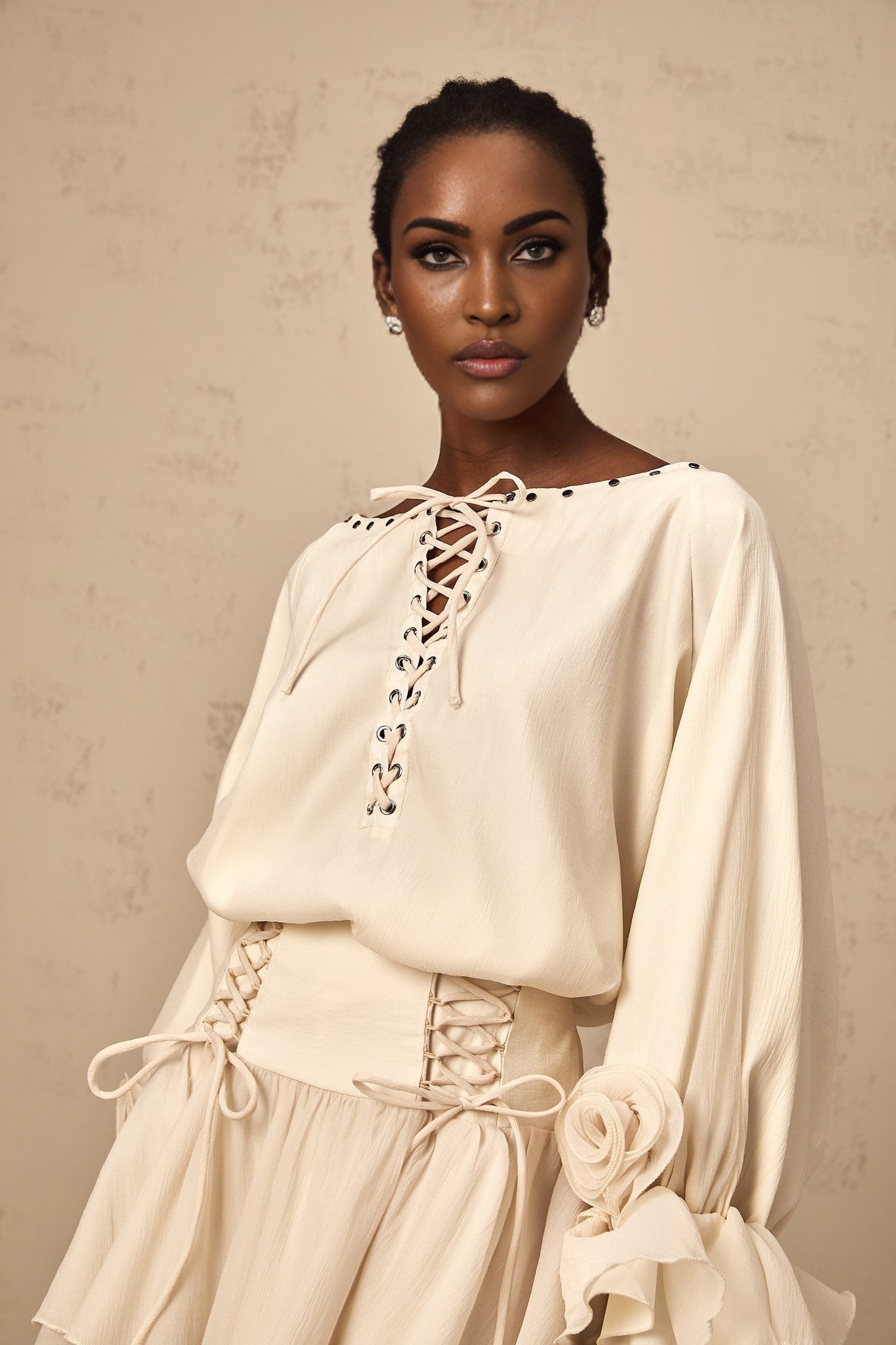 Woman wearing a matching blouse and skirt set in light fabric with ruffles and self tie details