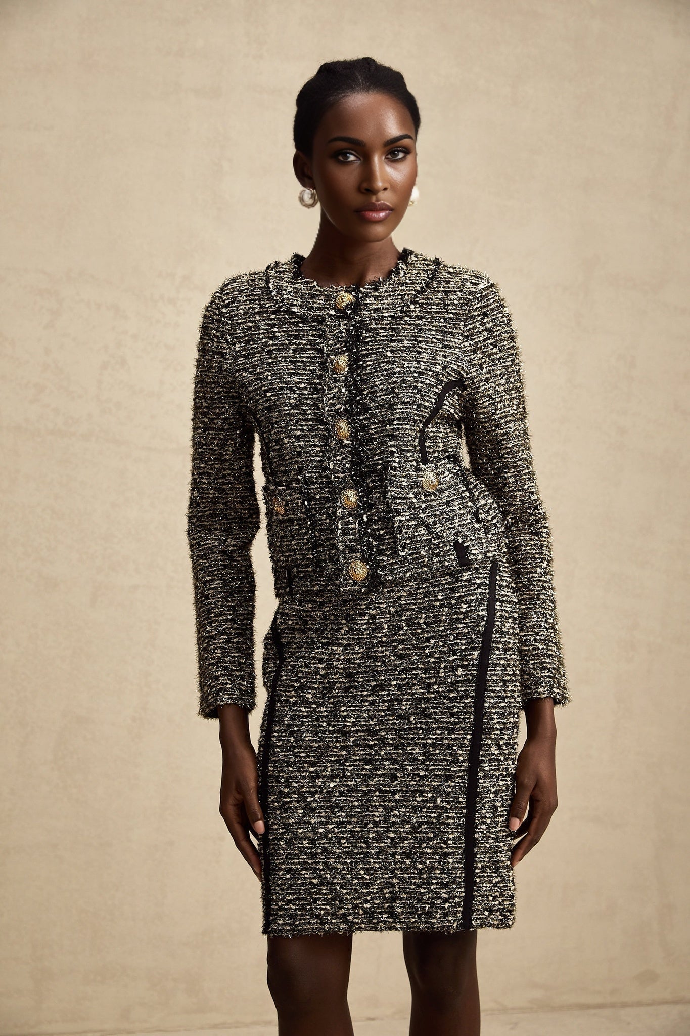 Woman wearing a matching jacket and skirt set in contrasting colors with shimmering lurex fabric details