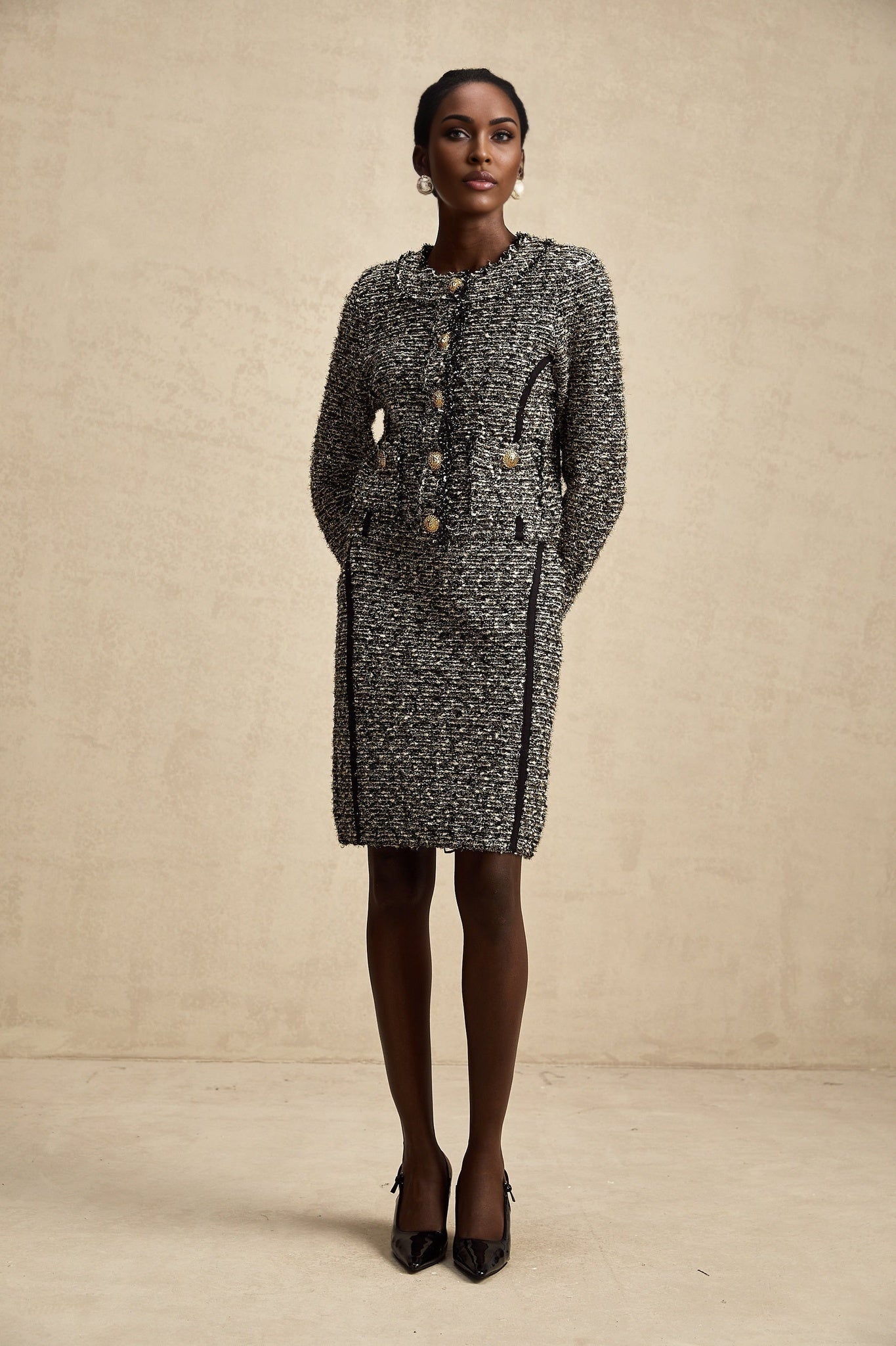 Woman wearing a matching jacket and skirt set in contrasting colors with shimmering lurex fabric details