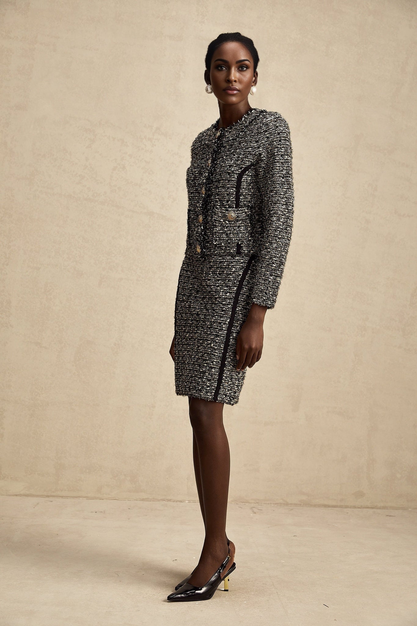 Woman wearing a matching jacket and skirt set in contrasting colors with shimmering lurex fabric details